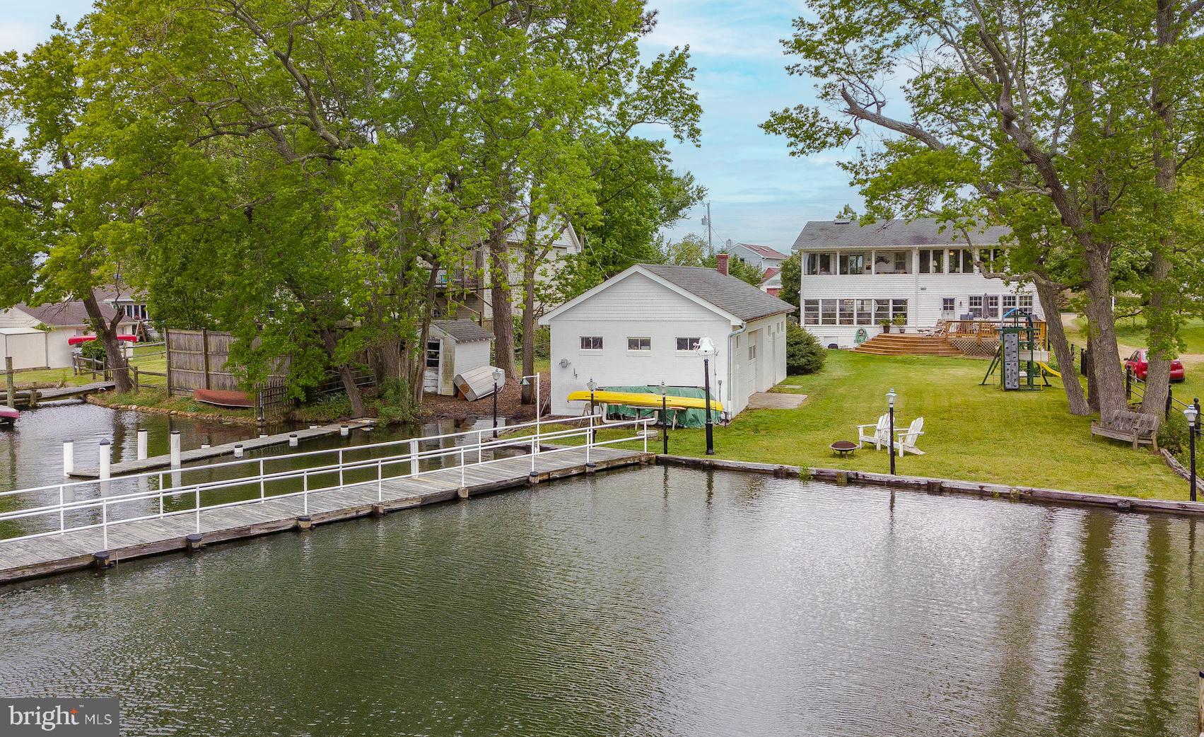 Charming Waterfront Cape Cod on Half Acre in sought after McKays Beach. Two (2) Piers with Water, Electric and Fish Cleaning Station, Private Boat Ramp, Boathouse/Covered Slip, Grandfathered Gazebo over the Water, Several Large Boat Slips and DEEP WATER on Herring Creek. The Enchanting Cottage was built in 1946 and has Original Hardwood Floors throughout. Stylish Kitchen with Silestone Countertops, Huge Island with Prep Sink, Gas Range and a Large Pantry. Cozy Living Room with Original Knotty Pine Walls and Wood Burning Fireplace. Bright Sunroom with Incredible Views. Two (2) Bedrooms on the Main Level and a Large, Lovely Primary Suite on the 2nd Level with Walk-In Closets. Family Room on 2nd Level could be 4th Bedroom/Den/Office if needed. Watch the Sunrise over the Creek on the Tranquil Veranda with Custom Boat Curtains for Three Season use that convey. Large Deck, One (1) Car Garage and a HUGE 70’ Workshop/Outbuilding. Community Beach Access to the River, Community Garden and a "Take a Book Leave a Book" Shared Library Box! You will fall in love with this Whimsical Property. Serene and Peaceful.