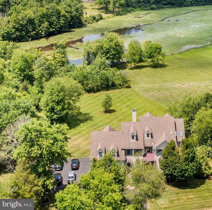 LAKE NOCKAMIXON – Welcome to a truly unique, custom built home backing to State Parklands with front row seats to Lake Nockamixon. Upon entering the gracious Entry, the lakefront views are just about to begin, with nearly every room enjoying the parkland & water views. The home’s main level features 10’ ceilings, 8’ Mahogany doors, extensive crown & custom moldings, with warm Mahogany flooring spanning much of this level. The inviting Great Room, with its floor to ceiling stone fireplace, takes center stage with nearly ceiling height windows embracing the view. The easy flowing floorplan, anchored by the gourmet kitchen, welcomes entertaining on many levels. The professionally outfitted kitchen w/furniture grade cabinetry, Wolf dual-oven range w/grill & griddle, a 42” Subzero, a Shaw dual-bowl farm sink, exotic hardwood countertops, walk-in pantry, butler’s pantry & a conveniently sized compact island make for a custom-tailored cooking experience. The open, yet formal feeling Dining Room easily accommodates large gatherings. Additional spaces on this level are the spacious private office with its own screened-in porch, a unique 2nd “Service Entry”, & remarkably spacious powder room with its own outside access – ideal for a future pool/cabana. The second-floor features hand rubbed random-width pine floors w/solid pine doors throughout. The generously scaled primary bedroom has tray ceilings, its own balcony, walk-in closets, a huge en-suite bath with vaulted ceilings, skylights, a claw foot tub, and walk-in shower. In addition to 3 more remarkably sized bedrooms w/spacious closets, a full hall bath & generous laundry room; the 2nd floor hosts an impressive, award-winning library (32' x 24') with vaulted ceilings, wrap around custom bookcases, cabinetry, millwork, museum level lighting & its own full bath. The finished 3rd floor currently serves as an additional office space but would make for an ideal “tucked away” Family or Game Room. The professionally finished walkout basement is smartly laid out with both public & private spaces that can be utilized in a myriad of ways. There is a full bath w/a personal cedar sauna, a nicely outfitted 2nd kitchenette, and spaces that are currently set up as a sitting room, a media room that is well suited for At-Home Schooling, a cozy den area w/wall mounted electric fireplace & a generous open-living area. The basement’s renovation in 2010/2011 incorporated a gravity-fed drainage system installed in such a way that renders a sump pump obsolete. ADD’L FEATURES: Newer Multi-Zone RHEEM HVAC Systems & Hot Water Heaters (2021); Payne Main Level A/C Unit (2018); Trane 2nd Floor A/C (2021); Aprilaire Air Cleaning/Filtration System Installed (2021); Anderson Series 400 Windows & Glass Doors; Hardie Plank Siding; Water Softener w/UV Filtration, Central Vacuum 1st & 2nd floors. A Generac portable 10,000kW gasoline generator handles the essentials. There are numerous Built-Ins & Custom Cabinetry throughout the home that convey with the sale, (ie: LR Entertainment Center, 2nd Entry Wall Units, Library Cabinetry, Bedrooms Built-Ins, etc.) At about a half mile to one of the lake's boat launches & 2.5 miles to Pennridge Airport, it's ideally located for a wide range of recreational activities. Just 60 minutes from Philadelphia's Center City & about 95 minutes to NYC. Property is under video surveillance - please do not drive up to home without an appointment.