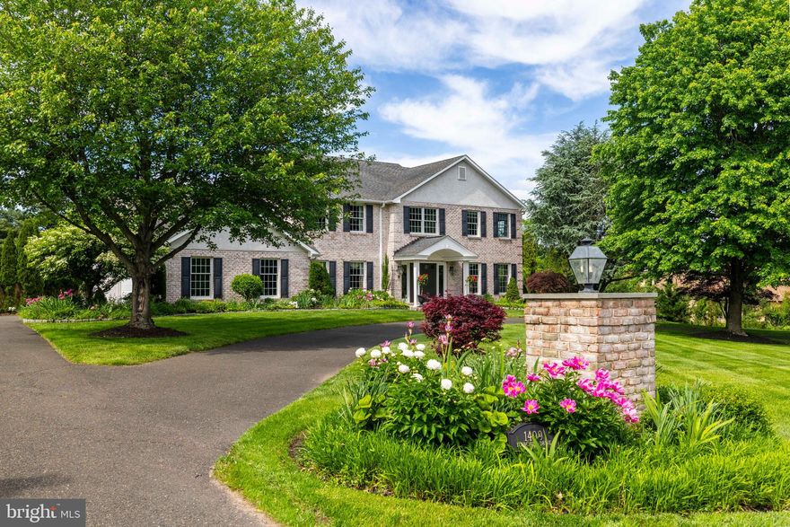 Set on a beautifully landscaped 1-acre lot in Gwynedd Estates, this whitewashed brick Colonial blends architectural elegance with thoughtful design and modern versatility. Framed by specimen plantings, lush perennial gardens, and mature trees, the home’s curb appeal is enhanced by a circular drive with pier lighting and a classically styled portico. A major architectural remodel transformed the first floor into an open-concept layout that maximizes light and flow. The vaulted-ceiling kitchen is the heart of the home, featuring custom maple and cherry inset cabinetry by a Lancaster County artisan, granite countertops, an oversized island and bar, a farmhouse sink, and top-tier appliances including a GE Monogram 6-burner gas range, Bosch dishwasher, and double wall oven. The adjacent mudroom adds built-in storage, beadboard detailing, and a second entrance to the backyard for easy clean-up after outdoor play. Detailed millwork—including coffered ceilings, crown molding, and wainscoting—adds timeless charm, while recessed lighting and warm hardwood or porcelain tile floors provide comfort. A family room with a custom cherry mantel, spacious dining area, and flexible living room offer ample room for gathering. Upstairs, the primary suite offers a double-sink vanity with engineered stone countertop, whirlpool tub, frameless glass shower, and a fully outfitted dressing/laundry area. A bonus room above the garage provides space for a guest suite, home office, or playroom. Hardwood flooring continues through all bedrooms, complemented by ceiling fans and solid wood paneled doors with oil-rubbed bronze hardware. The fully finished lower level mirrors the home’s style with beadboard, chair rail, and white columns. It includes a large open space, a flexible-use room with two closets, recessed lighting, and extensive built-in storage—ideal for a kids' playroom, craft room, gym, or second office. Two egress windows and a radon mitigation system add peace of mind. Outside, enjoy over 800 SF of hardscaped flagstone patio with curved steps, built-in brick wall to frame the patio, undermount lighting, and two natural gas hookups for grilling or heaters—perfect for entertaining. Significant exterior enhancements include Anderson 400 series windows, Azek trim, professionally painted stucco exterior, and a Generac generator. The roof was previously replaced and remains in excellent condition. Additional system upgrades include a 75-gallon hot water heater, sump pump system, attic fan, and upgraded electrical panel. Located in the top-ranked Wissahickon School District with walkable access to Gwynedd Valley train station, this home is minutes from vibrant downtown Ambler, the Whole Foods shopping plaza, refreshed YMCA, and major highways. Every detail was designed with intention, making this an extraordinary place to call home. Call for your showing TODAY!