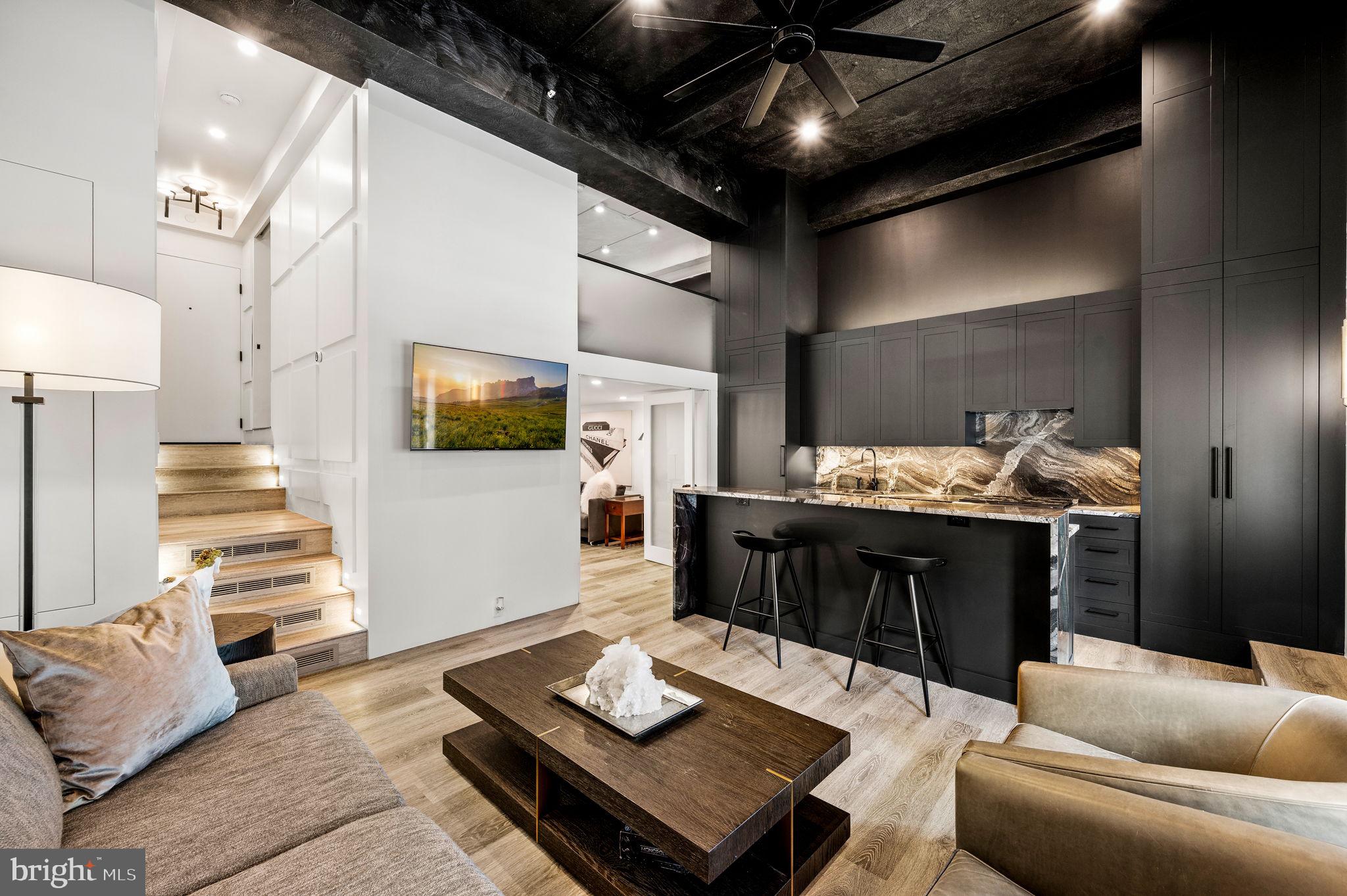 Parc Rittenhouse 710 defines exclusive and elevated living. The degree of opulence, rarity of features and level of customization is above and beyond in this extraordinary bi level 2 bedroom 2.5 bath luxury condominium. Creative minds of John Toates Architecture and Farnady Interiors along with the skills of Weaver Construction came together to create this one of a kind living space. Upon entering, take note of the custom millwork on the walls and the cleverly disguised storage throughout the home. Stair lights illuminate the steps down to the open living space with south facing windows offering a peek of Rittenhouse Square. This breathtaking space features soaring 14 ft beamed ceilings, a lit niche space for displaying artwork, brass wall lighting, and a ceiling fan. The sleek kitchen is equipped with a 4 seat breakfast bar, granite counters, Monogram appliances including an oversized gas stove with vented hood, built-in microwave, custom pantry, soft close cabinets, abundant storage, and LED lighting under the cabinets and island. Frosted glass custom bifold doors open into the second bedroom offering a deep closet with a built in safe and an ideal desk/office space. The ensuite bathroom features 12×24 ceramic tiles, LED framed wrap around wall mirror over a white Carrara marble sink, and a floating toilet. The second floor loft style primary bedroom has wall to wall custom closets and overlooks the first level through a frosted glass half wall. The luxurious ensuite black and white bath is complete with oversized tile work, floating toilet, wrap-around mirror framed with LED lights over a white Carrera marble sink. Just below find a separate laundry room equipped with a full sized stacked Whirlpool washer and dryer, a large closet with a handy outlet perfect for an iron or a steam press. The neighboring powder room is to delight guests with its John Paul Gaultier flocked wallpaper, Carrera marble sink, and geometric tiled floor. This sophisticated condominium is designed to perfection. Extraordinary features to note are sound and fire proofed walls, an independent HVAC system which is unique to the south side of the building, and recessed and accent lighting to enhance the ambiance. The many well thought out details make this a true work of art and a must see to appreciate. A parking license for the building is available for an additional $100,000. Residents of Parc Rittenhouse enjoy a beautiful landscaped deck with outdoor pool and jacuzzi, meeting and conference rooms, a state of the art fitness center, a stunning lobby with a fireplace, and 24 hour doorperson. Walk out your front door and enjoy all that Rittenhouse Square has to offer including Parc Bistro and many other restaurants, cafes, shopping and much more.