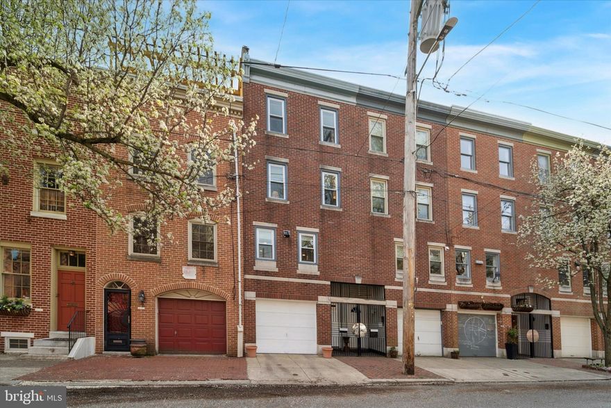 Welcome to 310 Queen Street, a charming 3-bedroom plus den, 2.5-bathroom townhouse nestled on one of Queen Village's most picturesque blocks. This 1,953+ sq ft residence seamlessly blends historic character with modern updates, offering a warm and inviting atmosphere.

Step into the spacious living room, where high ceilings,  hardwood floors, and a wood-burning fireplace create a cozy ambiance. Large windows overlook a generous private patio/deck, perfect for outdoor entertaining. The kitchen features a separate dining area with lovely hardwood floors, ideal for family meals and gatherings.

The second level boasts two well-sized bedrooms with hardwood floors and a full bathroom. The third level is dedicated to the master suite, complete with a sitting room or den that could serve as a fourth bedroom. A finished lower level provides additional space for an office or playroom. Enjoy the convenience of an attached garage, a rare find in this neighborhood.

Located in the heart of Queen Village, this home offers easy access to the vibrant South Street, historic Fabric Row, and the scenic Delaware River waterfront. The neighborhood is known for its eclectic shopping, diverse dining options, and rich history, including landmarks like Old Swedes' Church. Families will appreciate the proximity to the highly regarded William M. Meredith School.

Experience the perfect blend of historic charm and modern living in this delightful Queen Village townhouse.