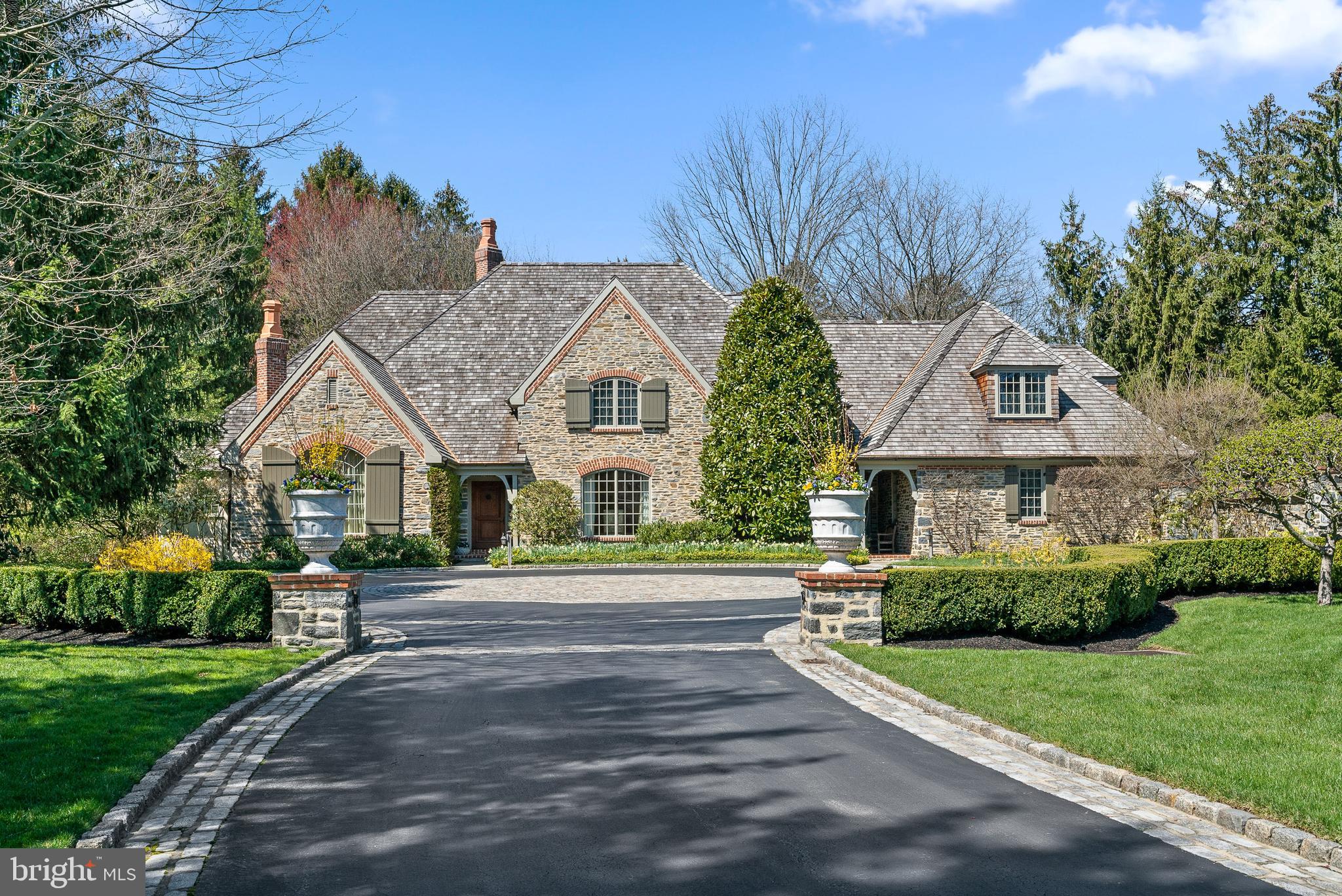 Experience luxury living at its finest in this custom-built French Colonial masterpiece located at 5 Andover Road, Haverford, nestled on a quiet street near the prestigious Merion Golf Club. Meticulously crafted by master builder, E.B. Mahoney, this exceptional residence exudes timeless elegance and superior craftsmanship, showcasing the finest materials and attention to detail. The main level boasts a spacious family room adorned with a wood beams and a grand fireplace featuring a custom limestone surround. Three sets of French doors open to a picturesque slate patio with a tranquil fountain, offering stunning views of the expansive lot. Additionally, the main level includes an inviting office/den with fireplace and built-ins, a gracious dining room with coffered ceiling and an attached butler's pantry, perfect for seamless entertaining. This stunning home boasts many architectural details, like reclaimed wood and travertine flooring, millwork, solid wood beams, moldings, curved archways and solid mahogany doors. The heart of the home lies in the well-appointed kitchen, featuring a center island with a Thermador cooktop, stainless steel appliances, Sub-Zero refrigerator, a charming breakfast room bump-out, and a dedicated wine storage area with wet bar. A luxurious first-floor primary suite awaits, complete with two full primary bathrooms and two separate closets/dressing areas, offering a private retreat. Two additional half bathrooms, convenient laundry room and attached garages complete this level. Ascending to the second floor, you'll find three generous bedrooms (one currently used as a gym/office) and two full bathrooms, both with double vanities and a tub/shower combo, providing ample space for family and guests. The lower level offers a partially finished area with a half bathroom, perfect for a game room or recreation space, adding an additional entertaining area. The lush, manicured gardens, specimen plantings and landscaping, expertly curated by Gale Nurseries, envelop the property, offering unparalleled privacy and tranquility. Enjoy the serenity of the in-ground pool and terraces, bordered by a graceful pergola, creating an idyllic setting for alfresco dining and entertaining. Conveniently located near Merion Golf Club and Merion Cricket Club, esteemed private schools, restaurants, the farmers market and shopping at Suburban Square. All this, and only minutes from local and regional trains, Septa R5 to Philadelphia and NYC.
