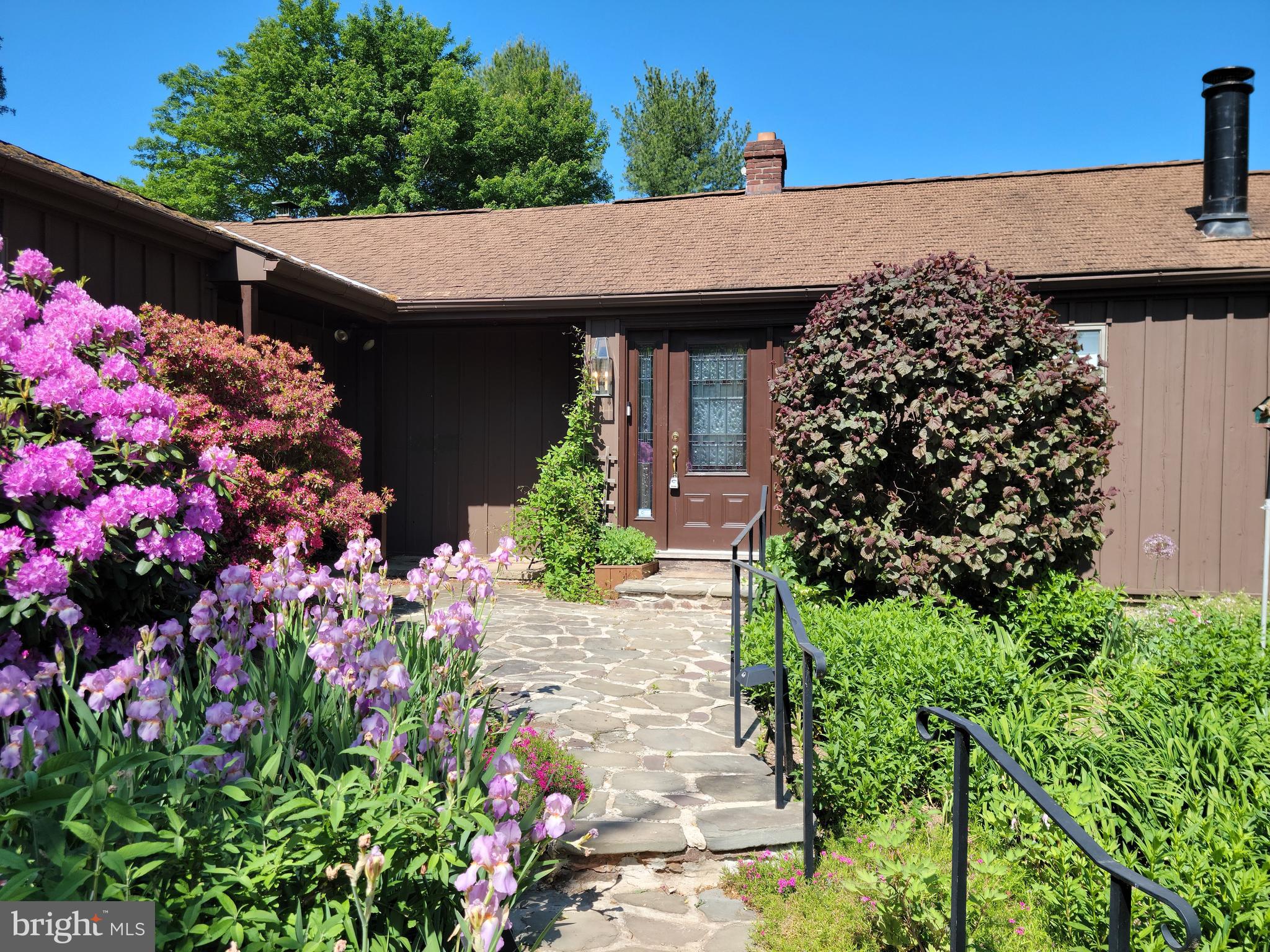 Welcome to 1279 S Hanover Street, where you'll be greeted by a lovely stone path adorned with beautiful mature flowering shrubs and landscaping. Step through the inviting lead glass door into a tiled foyer, and immediately on your right, you'll discover the first of two living spaces. This family room offers a unique two-level design, complete with built-in bookcases and a cozy fireplace. Through the sliding glass doors, you'll be delighted to find a spacious covered deck, perfect for enjoying the outdoors on a sunny day. To the left of the foyer, you'll find a large living room featuring a charming brick fireplace. Sliding doors open up to a stone patio, providing a lovely view of the surrounding gardens. Moving on to the bright kitchen, you'll be pleased to find ample cabinet space, wall oven and built-in microwave, stainless steel refrigerator, and cooktop stove. The pantry is equipped with three walls of floor-to-ceiling cabinets and an additional refrigerator. Adjacent to the kitchen, a cozy nook overlooks the gardens and can serve as a delightful breakfast room, sunroom, or a place to cultivate your indoor herb garden.
The primary bedroom's location off the living room provides privacy and features a vaulted ceiling adorned with a ceiling fan. Sliding doors open up to a balcony that offers a peaceful view of the yard, graced by mature trees. A walk-in closet leads to the primary bathroom, which features a tub and shower combination. Finishing off the main floor is a conveniently located laundry room, boasting a double sink and plenty of cabinets and shelves for storage. Continue down the hall to find the second main floor bedroom, with a walk-in closet and a bathroom equipped with a walk-in shower. 
Moving downstairs, you'll discover two additional bedrooms. One of these bedrooms has its own outside entrance and has a full bathroom. This versatile space can easily serve as an office or flex room, catering to your specific needs.
Completing this 3.18-acre property is a two-car garage and an unfinished basement, providing ample space for your vehicles and offering potential for customization according to your preferences. Come see all this home has to offer!