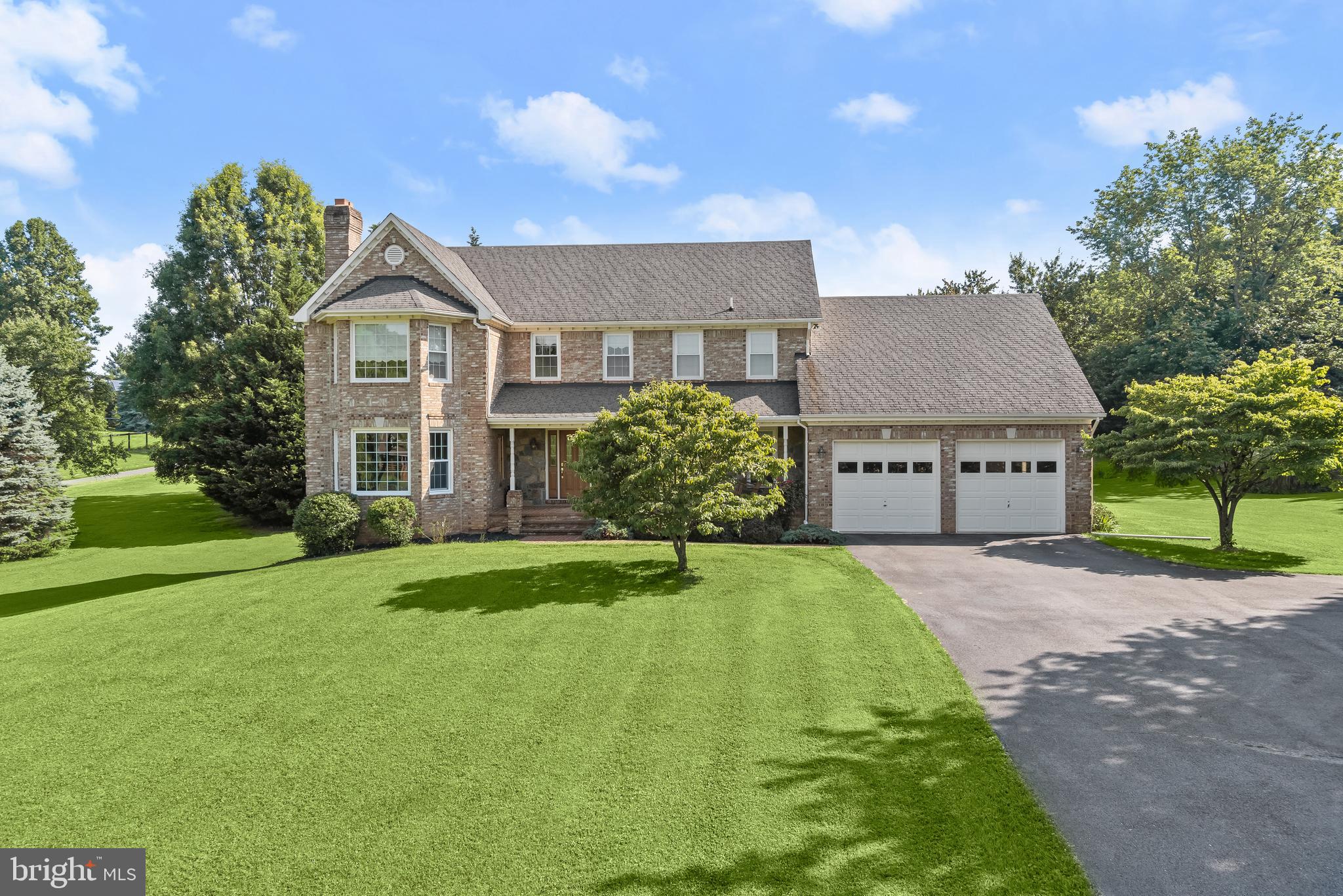 Welcome to your dream home at 17580 Hardy Road, perfectly situated at the intersection of peaceful country living and everyday convenience. Custom built by master brick masons and beautifully maintained and upgraded by its original owner, this all-brick residence offers 5,000 square feet, light-filled living space inside, plus outdoor venues ideal for both entertaining and daily comfort. A generously sized front lawn, private drive, brick walkway, manicured landscaping, and a welcoming front porch prepare you to fall in love with a very special lifestyle surrounded by nature’s bounty. Inside, the center foyer is flanked by living and dining formals with gleaming hardwood floors, elegant architectural details and a bay window with framed vistas that calm and enliven all at once.
The heart of the home is a spacious, open-concept kitchen featuring granite countertops, stainless steel appliances, a commanding central island with a breakfast bar, pantry, and wrap-around wood cabinetry enhanced with a designer tile backsplash and picturesque views. Adjacent to the kitchen, sunlight streams and bounces through a bay window, bathing the breakfast area with morning sun while the thoughtful open plan design unfolds seamlessly into a family room with a beamed ceiling and rusticated stone fireplace surround offering a cozy wood burning fireplace with a relaxed and casual feel and atrium access to invite outdoor living at its finest. Enjoy outdoor venues daily or host gatherings large and small on an expansive low maintenance deck, brick gazebo, or stone grilling patio with access to the garage through a secondary service door. This spectacular home presides over a tree-fringed 3.3+acre level lot providing endless outdoor entertaining venues for sports, hobbies and activities of all kinds. A front loading two car garage provides inside access to a mud room and laundry center adjacent to the kitchen. On the other side, the main level is concluded with a well-appointed private study tucked away in an idyllic location, standing at the ready to foster any amount of creativity or productivity for a day of work or study.
Upstairs, the generously sized primary suite boasts a large window seat, sitting area, walk-in closet, and a fully remodeled spa-inspired luxury bathroom complete with an expansive double vanity, and a large open shower with designer tile and rain shower head. Three additional spacious bedrooms and a renovated hall bathroom provide comfortable accommodation for family or guests. Downstairs, a full daylight, walk-out lower level offers a sun-filled versatile layout with a recreation room, wood stove, game area or playroom, a fully upgraded full bath, and a flex space for optional storage or exercise area is also included.
Outside, enjoy the privacy and serenity of a professionally landscaped property with mature trees, front, back, and side yards, tree-lined boundaries, and plenty of room for hosting, gardening, playing, or just for peaceful relaxation. Perfectly located on a quiet low-traffic within a top-rated school district, this exceptional home is just minutes from commuter routes, shopping, and dining in charming Downtown Mount Airy. Don’t miss this rare opportunity to enjoy comfort, space, and timeless style with endless outdoor living options in one of the area’s most desirable neighborhoods. Schedule your private tour today!