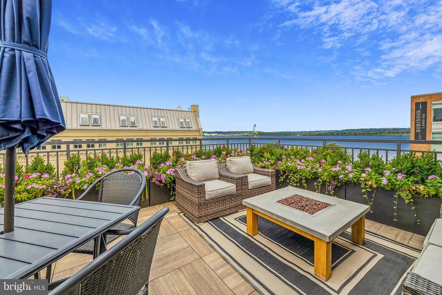 This stunning contemporary corner unit townhome sits only steps away from the waterfront in Old Town, Alexandria. Found at the edge of Robinson Landing with direct view of the Old Dominion Boat Club and Potomac River, it’s surrounded by shops, parks, restaurants and enjoys access to the development's long list of amenities. Amenities include: use of full gym, concierge, indoor mailbox, conference room, library, lounge, pet spa and yoga center. The home comes complete with an elevator with access to all 4 floors, an attached 2 car garage, tall windows on three sides filling rooms with natural light, high ceilings and more. There are 4 bedrooms and 4 and a half bathrooms. The primary bedroom is outfitted with 2 walk-in closets and an en suite with double sinks and a spacious shower. The main level features an open concept floor plan with the kitchen sporting Snaidero cabinetry, Thermador appliances, high ceilings, gas fireplace and a custom built-in bar. Finally, enjoy golden hour on the rooftop terrace with stunning views of the Potomac River while enjoying the space’s full outdoor kitchen, grill linked to natural gas, fire pit, box planters and comfortable patio furniture. Two block stroll to the 100 block of King Street & 1.3 miles to King Street Metro. A few miles to airport,  Amazon H2Q and Washington D.C.  - Patio furniture on roof conveys including: grill connected to natural gas, propane fire pit, patio table with umbrella and 4 chairs, all box planters and patio chairs with sofa.