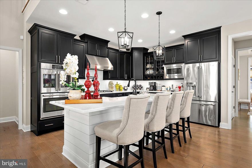 Introducing 19218 American Holly Road – Location, location, location! It is a unique opportunity when a Rehoboth Beach home nestled between open community space and a tree lined pond in the sought after Arbor Lyn community becomes available. Come and see this 5400+ square foot meticulously maintained 5 bedroom, 5 bathroom home. 19218 American Holly Road is Schell's popular Lilac model. In addition to being one of the most desirable floor plans and situated on a premium lot, the numerous upgrades selected during construction—along with the enhancements added by the current owners (list available)—make this home a true standout. From the moment you arrive the curb appeal draws you up to the spacious covered front porch. Once inside, the capacious foyer provides a seamless flow past an office/den, powder room, laundry room with access to the two car garage and into the stunning fully upgraded kitchen, open dining and soaring great room with vaulted ceilings, cathedral style windows and a floor-to-ceiling stone gas fueled fireplace with a raised hearth. The kitchen and dining room are impressive with top end appliances and finishes perfectly designed to welcome the gathering of your family and friends. Seamless wood floors throughout the main level lead to a first floor primary suite that enjoys views out to the pond and is fully separated from the upstairs guest rooms providing total privacy for you and your family or guests. The four large upstairs bedrooms include a second primary suite featuring a large walk in closet and beautiful ensuite bath. A private covered porch off the second floor primary has pond views.  A second full upstairs bath serves the other three guest rooms. The second floor also features an open concept loft dramatically overlooking the living room below where you will find yourself lingering in late afternoon as western sunlight floods through a large plate glass window providing stunning horizon views of sunsets. Downstairs off the sunroom extension of the living room is an enclosed three season porch which leads to a large paver patio, a gas hookup on the patio is ready for your summer grilling goals. From the three season room or patio you will appreciate seeing the inspiring wildlife and seasonal foliage that border the tranquil pond throughout the year. One of the most exciting spaces in the house is the fully finished lower level featuring a stunning wet bar with ice machine and custom cabinetry to host even the largest gatherings. The lower level also features a gorgeous movie room with insulated paneled walls and ready-to-go electronic hook ups for your choice of viewing experiences. There is a one half bath and two large storage rooms with plenty of shelving that conveys to complete the lower level. Perfectly located just minutes from Rehoboth Beach and boardwalk, you’ll enjoy easy access to everything! When you choose to stay close to home and spend time with your friendly neighbors you'll be glad that Arbor Lyn offers resort-inspired amenities including a pool and clubhouse with outdoor fireplace. This exceptional home presents a rarely available ready made opportunity of real value. At only $194 sq foot there simply is no better deal in Rehoboth Beach! Rentals of 7 days or more are permitted. Nearly brand new top end home furnishings could also be included in sale. The complete list of upgrades and improvements is available for review. The house is under a transferable warranty. Whether you're seeking a luxurious family home or a convenient coastal getaway, this well located property truly has it all.