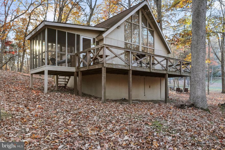 MULTIPLE OFFERS RECEIVED!!!  FINAL AND BEST OFFERS DUE BY 5 PM TUESDAY, NOV 14TH!!! 
 Cozy 2 bedroom, 1 full bath with a full wall of glass windows for viewing outstanding wooded view! Open Kitchen/Living area concept.  Upstairs loft.  Screened in Porch and a deck.  Outdoor space is perfect for outdoor fun or just relaxing around the firepit.  Heat Pump replaced THIS YEAR!!  Hot Water Heater is only 3 years old! Perfect for year round living, vacation getaway or Airbnb.