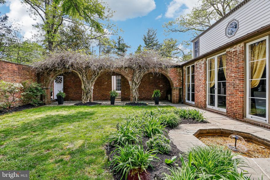 Designed by renowned Princeton architect and professor Francis Comstock, this Western Section unique home was built as his residence in 1929. Second owner, artist Miriam Whitney Coletti incorporated mid-century modern features during her 50-year tenure. This one-of-a-kind, 5 bedroom and 5.5 bath gracious home juxtaposes traditional with transitional. Entering the Welcome gate, you are transported to a charming Tuscan courtyard with trumpet-vine covered brick arches and fountain. The clavo-trimmed front door opens into a foyer that provides access to the beautiful new addition through French doors, and the original main house. This private addition boasts a large living room with walnut floors, coffered ceiling and French doors that open into the yard. The exquisite oak library, designed around circa 1800s antique glass-door bookcases imported from London, features a double-sided gas fireplace shared with the living room, hickory floors with compass rose inlay and additional built-in open bookcases. As you exit the library to a separate entrance from the courtyard, the mudroom with beadboard lockers opens to a half-turn staircase descending to a finished 9' ceiling basement with a second family room, full bath and gym. The addition is equipped with a tankless water tank, high velocity HVAC and generator. No detail was spared in this stunning addition with custom millwork and doors to match the original house. Entering the main house, the long hallway showcases original marble floors, key-motif ceiling trim, and full-height French doors that access the courtyard. The first floor features a large dining room with wainscoting and domed bamboo alcove opening through French doors to the fountain in the courtyard, cozy kitchen with breakfast area and butler's pantry, large family room with wood-burning double-sided fireplace to breakfast area and a wall of ceiling-to-floor windows and sliding door accessing an elevated bluestone patio and expansive backyard, quaint brick-wall sunroom with arched window and door, a second office with half bath and an ensuite bedroom with original claw-foot tub. From the foyer, the main staircase with key-motif iron balustrade leads to a separate ante space with a bedroom, bath, laundry room, and sitting room with pair of sliding doors opening to double balconies. Upstairs main hallway leads to an ensuite bedroom, a second bedroom, and primary suite with gel fireplace and room-width windows spanning wisteria vines and wooded vistas. In addition to the raised patio, steps lead to a private ground-level bluestone patio sitting area and second patio with pizza oven and grill, and hot tub. Beautiful seasonal plantings provide color for months in this park-like setting. Ideal home for entertaining both large and small gatherings. Cocktails in the courtyard followed by dinner in the dining room and dessert on the patio overlooking the beautiful gardens. You may be the only owners in Princeton to host your own home-baked pizza parties! Close to Greenway Meadows and downtown Princeton. Top ranked Princeton Public Schools.
