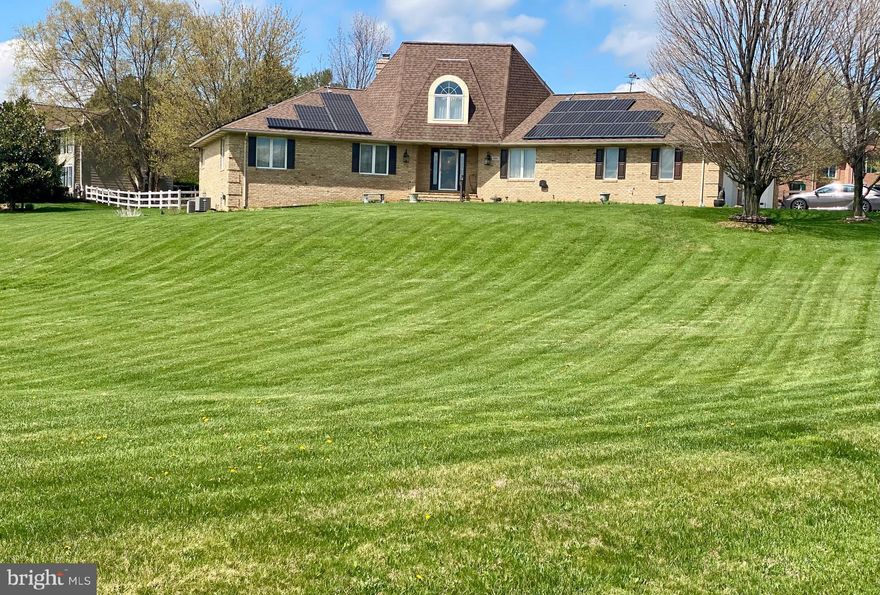 Warm and welcoming!  Come home to this spacious single-level living in this Ausherman-built brick rancher with bonus upper level!  Floor plan is perfect combination of open living with private areas too.  As you pull up to this beauty, you will be greeted by the rolling front yard and park next to the three-car garage.  The portico welcomes you to come into the spacious foyer with spiral staircase. To the right, you have a traditional feel of living room with adjoining dining room.  Heading straight back, you will see a grand kitchen with granite, center island with seating, and separate breakfast space.  To the left of the kitchen is a light-filled sunroom which provides exit to the deck overlooking the back yard.  Back inside, as you walk from the kitchen towards the front door, you will step down into a cozy family room with wood-burning fireplace.  The back of the family room opens to a small hall, home to the primary bedroom and bath,  and laundry.  From the entry immediately to the left is a pass-through library leading to the 2nd bedroom (now used as a home office).  A powder room is just to the right.  Climbing the spiral staircase, the upper level opens to a private study area overlooking the front yard.  Two additional bedrooms and a full hall bath complete the upper level.  The lower level of the home is used primarily for storage at this time, but some areas are partially finished.  There is a full rough in for a future bath and a walkout to the yard.