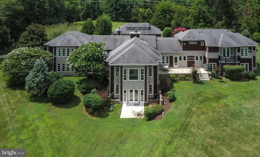 Welcome to a high-end 5 bedrooms, 4 full baths custom built home in Megills Crossing Equestrian Community just 1.5 miles away from the heart of Main Street in Clifton. This sprawling almost 5,400 sq. ft. custom modern day arts and craft home is nestled on 5 acres. Located on the north side of Clifton, it provides a convenient commute. At the end of the day, you will find this home offers a serene place to come home and relax. Inside, the home is designed to blend modern conveniences with artisan craftsmanship creating a welcoming luxurious vibe. You are going to want to move in immediately! Upon entering, the breezeway serves as both a dining room and circulation space, connecting the entry and living room to the gourmet kitchen and family room. A wall of windows across the back of this open concept Craftsman house plan makes the home bright and airy. The rooms are made to be very versatile. We chose to change the gorgeous vaulted and beamed family room off the kitchen into a modern day dining area. The large kitchen island and  walk-in pantry give you and your family terrific storage space. There is a separate kosher preparation kitchen off the main kitchen with 2 extra dishwashers (perfect for catering). The kitchen comes outfitted with top-of-the-line appliances to include a Lacanche range for the gourmet chef and expansive windows framing picture-perfect backyard views. The mudroom entry into the laundry room is filled with custom wall sized cabinets as you enter into the oversized laundry room with inset cabinets and lots more storage. There will be no complaining about doing laundry in this perfectly designed space! The owner's suite extends the entire depth of the bedrooms below and features a private sitting room with balcony access. The very private owner's suite comes with a spacious bathroom, free standing tub,  walk in shower, 2 separate commodes, 2 separate vanity areas and 2 separate large walk-in closets completely apart from the owner's bathroom. There are 2 additional ensuite bedrooms on the right wing of the home. The lighting throughout the home is very modern and new.  The fully open lower level recreation room provides plenty of space for games, media, and relaxation with lots of natural light. The expansive 4 car garage, designed to fit the biggest vehicle possible, has a second floor above with an unfinished large bonus room with a bathroom rough-in (almost 800 sq. ft.). Think au-pair/ mother-in-law suite/ art studio...options are endless.  However you choose to live, this luxury home accommodates! It's like owning your own five-star resort, and all the work has been done for you! All you need is a packed bag and the keys and, of course, furniture. Additional highlights include 6 zoned HVAC, 2  large water heaters, a side storage room, - you never know when this might come in handy - and workshop in the garage. This home is timeless with classic American architecture for contemporary living.