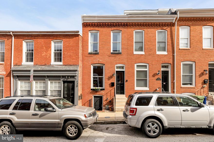 If you’ve been waiting for a Federal Hill home that actually gives you space to live, is full of charm, and has a garage… this is the one.
122 E Ostend Street blends classic character with a layout that just feels easy. A traditional brick facade and stained glass transom welcome you inside, where a sweet vestibule with vintage tile sets the tone. From there, the home opens into a light-filled front living and dining space, where original hardwood floors and a large window bring in that warm, natural light that makes all the difference in a rowhome. 
The layout is refreshingly flexible. The current owners have created multiple living spaces that can shift with your day, whether you're hosting, working from home, or simply looking for a quiet place to unwind. The kitchen sits right at the center, with plenty of cabinetry, stainless steel appliances, and a charming little pass-through window to the living space that makes you feel more connected. 
Toward the rear, a more relaxed living space feels like a hidden retreat, complete with a powder room and French doors that open to a private brick patio… the kind of spot that’s perfect for slow mornings, evening dinners, or letting a pup wander outside. And just beyond that, something you almost never see in Federal Hill: a two-car garage. It’s the kind of feature that quietly changes your day-to-day in the best way.
Upstairs, three bedrooms and two full bathrooms offer a comfortable and inviting second level. The primary suite sits at the front, featuring a clawfoot tub, separate shower, and soft light filtering in from above through transom windows and a skylight. In the rear, the back bedroom opens to its own private balcony… a small but special city escape.
The unfinished basement provides ample storage and houses the washer and dryer, giving you all the practical space you need without sacrificing the charm above. 
And then there’s the location. Perfectly positioned between Riverside Park, Federal Hill Park, and Cross Street Market, you’re truly in the middle of everything… the kind of place where your favorite spots are just a short distance away, and every day feels a little more connected to the neighborhood.
It’s a home that offers space, character, and that rare balance of city living with just a little extra room to breathe.