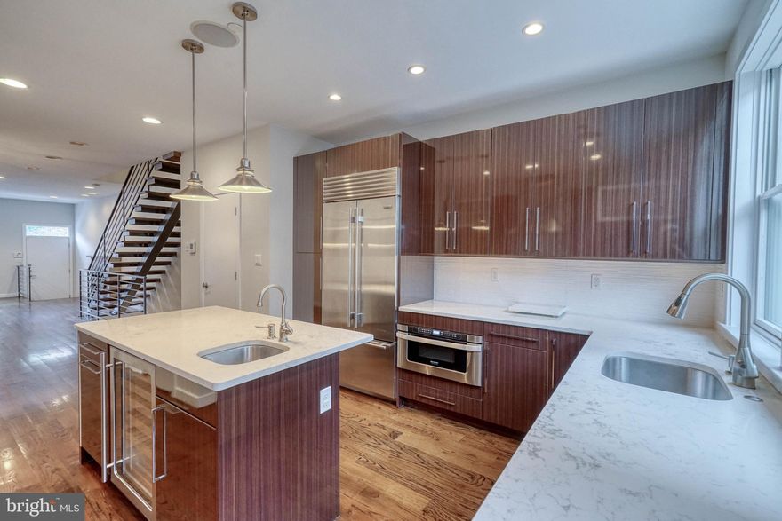 Set on a tree-lined block in Philly's Graduate Hospital neighborhood, you'll find 728 S 18th St. This modern 3-story home offers 4 beds, 3 full baths, 2 half baths, a finished basement, and three outdoor spaces: a patio, a roof deck, and a balcony off the primary bathroom. The home's main level is completely open, with beautiful hardwood floors extending throughout. A gas fireplace centers the living area, where tall windows fill the space with natural light. A hanging light fixture helps define the separate dining area. Past a powder room, the stunning chef's kitchen is adorned with high-gloss wood grain cabinetry, granite counters, Wolf & Sub-Zero appliances, a pantry, and a center island with seating and a wine fridge. Out back, the secluded patio is the perfect spot to relax with a morning cup of coffee or an evening glass of wine. The finished lower has a bonus space, ideal for a home theater or playroom, a full bathroom, a huge bedroom, and storage closets. On the home's second level, two large bright bedrooms with excellent closet space sit at opposite ends, flanking a full bathroom and laundry closet at the center. The third level is dedicated to the primary suite. There's a spacious bedroom framed by bay windows, two custom walk-in closets, and a luxurious ensuite bathroom equipped with a double vanity, a glass-enclosed massaging rainfall shower, and access to a peaceful balcony. Finishing the home is a wet bar and powder room that lead to the expansive roof deck. With tons of space to spread out and picturesque views, it just needs a personal touch to be transformed into an entertainer's paradise or a garden oasis. 728 S 18th St's smart-home features include hardwired speakers throughout and app-controlled security and climate. In addition to all that's inside, this fantastic location earns a Walk Score of 99! It's close to shopping and dining on South St, the extensive Schuylkill River Trail, and idyllic Rittenhouse Square. Kid-friendly Marian Anderson park is a block away - with an awesome pool for the summer months. Public transit makes getting around the city easy, plus there's quick access to the University of Penn, Washington Ave, and I-76. Schedule your in-person or virtual tour today!