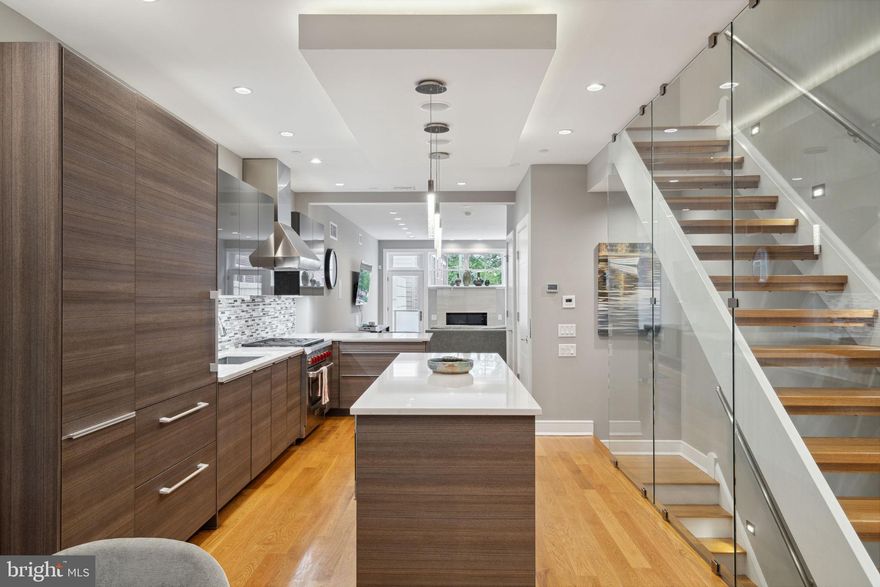 Nestled in the heart of charming Bella Vista, this stunning modern townhome was built in 2017 and boasts over 4000 Sq Ft of luxurious living space, complete with 5 bedrooms, 4.5 bathrooms, GARAGE PARKING, an Elevator to all floors, and a roof deck with breathtaking city views. The main level offers an expansive open plan living space, with a spacious dining area and an exceptional state-of-the-art kitchen fitted with custom walnut cabinetry by Poggenpohl, an integrated Sub Zero refrigerator, a 6-burner Wolf range, sprawling quartz countertops, and a peninsula with counter seating. The sun-splashed living room is anchored by a tiled gas fireplace and adjoins a tranquil outdoor patio space with unobstructed views down Perth Street into Cianfrani Park. In addition to the vast open living space, the main level offers a powder room and a cozy den/study with a large window overlooking Bainbridge Street. A dramatic wall of glass encloses the floating staircase leading to the upper floors and allows natural light to flow freely throughout the main level. The second floor offers two large bedrooms, each with en suite baths and ample closet space, as well as a convenient hallway laundry room with side-by-side washer dryer and a utility sink. On the third floor, the spacious primary suite features a balcony overlooking Bainbridge Street, an extra large walk-in closet with custom built-ins for organization, and a beautifully fitted en-suite bath with a walk-in shower, double vanity, and heated floors. The additional third floor bedroom could be used as a home office, nursery, den, or yoga space and features a large south-facing balcony with . The trellised roof deck crowns the house with peerless 360 views of Center City. The fully finished ground level includes a fifth bedroom and another gorgeous full bathroom, perfect for an in-law, au pair, or guest suite with easy access to the garage. Ideally located in the highly sought-after Meredith School Catchment, steps from Cianfrani Park, Palumbo Park, Seger Park, Whole Foods, Italian Market, Washington Square, and many delicious neighborhood restaurants. With approx. 4 years left on the tax abatement, this is luxury living at its finest.