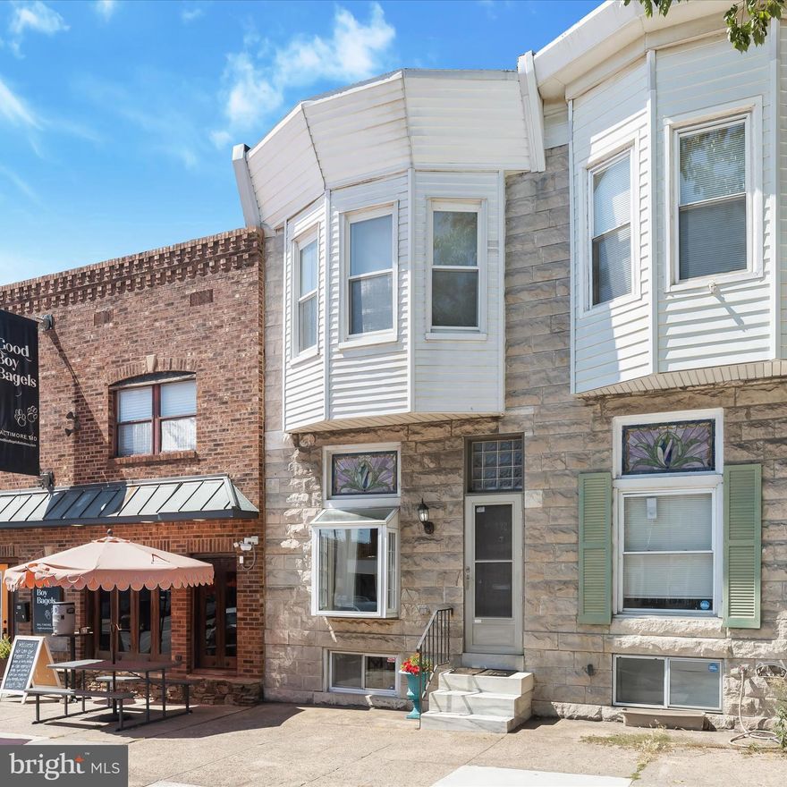 Historic charm meets modern convenience in this inviting rowhome in the vibrant Brewers Hill neighborhood. The bright and welcoming living room features rich hardwood floors, an exposed brick accent wall, and a pleasing neutral palette that flows throughout the home. A decorative stained-glass window and a deep box window, perfect for plants, pets, or décor that add unique character. The living room transitions seamlessly into the dining area, highlighted by a contemporary ceiling fixture, before opening to the eat-in kitchen. Here, granite countertops, a peninsula breakfast bar, stainless steel appliances, a gas range, and a ceiling fan create a stylish and functional space for cooking and gathering. Step right out from the kitchen to the deck for al fresco dining, with stairs leading to a rare and highly desirable two-car parking pad. Upstairs, the primary suite offers a bay-style bump-out window and a private en suite bath. The second spacious bedroom enjoys access to its own private upper deck with city views. The finished lower level expands your living space, serving easily as a recreation room, home office, or potential third bedroom. A full bath, laundry room, and walk-out access to the parking pad complete this versatile level. All of this comes with a sought-after Brewers Hill address; steps from the new neighborhood bagel shop, The Shops at Brewers Hill, popular Mobtown Brewing Company, nearby Canton hotspots, and just minutes to the Johns Hopkins Metro station. This home truly checks every box.