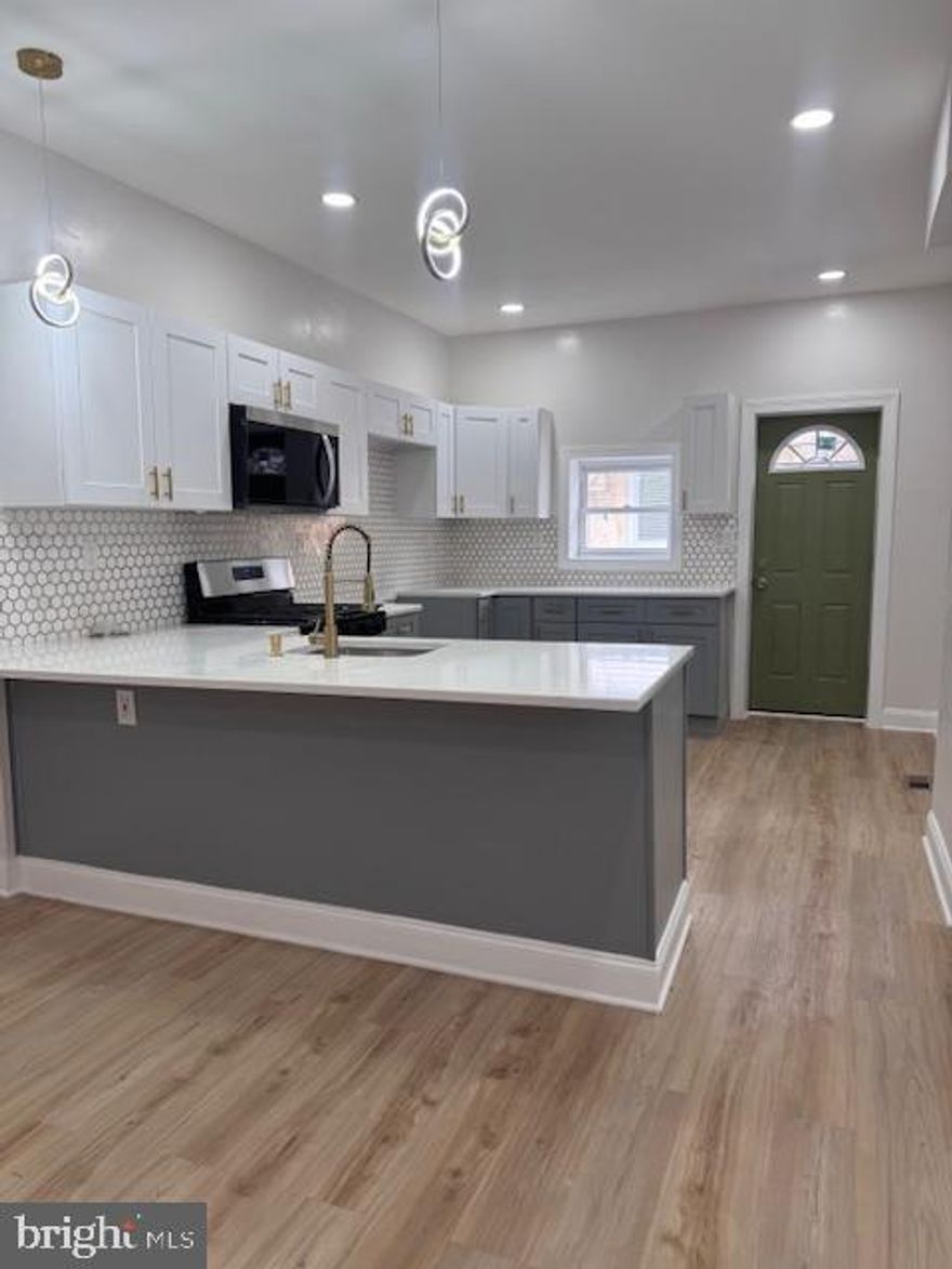 **Additional/Professional Photos Coming Soon**
Welcome to 5831 Washington Avenue, ideally situated in the Cobbs Creek section of Philadelphia. This beautifully renovated residence is set along a picturesque, tree-lined block and offers exceptional access to University City and Center City Philadelphia, making it a convenient location for work, dining, and entertainment. The home is also located near Cobbs Creek Park and just minutes from the shops and local eateries along Baltimore Avenue. As you approach the property, you are welcomed by a classic concrete front porch—an inviting space for outdoor lounging and everyday relaxation. Inside, the home features a thoughtfully designed interior with durable flooring, high ceilings, recessed lighting, and a seamless open-concept layout that flows effortlessly into the newly renovated kitchen. The kitchen is appointed with soft-close cabinetry and an elegant gold-and-white accented backsplash, creating a refined and modern aesthetic. Direct access from the kitchen leads to the rear outdoor space, where a newly constructed deck extends the living area and provides additional space for entertaining or relaxation. The fully finished walk-out basement adds exceptional versatility, featuring a newly updated full bathroom and porcelain tile flooring well-suited for the space. Recessed lighting enhances the bright, polished feel, while the layout allows for a family room, media area, or entertaining space. A separate rear room offers flexibility for a home office, fitness area, or additional private use. The laundry area is also conveniently located on this level.
The second floor continues the cohesive design with consistent vinyl flooring throughout and includes four spacious bedrooms, each featuring recessed lighting. The primary bedroom offers high ceilings, an exposed brick accent, generous closet space, and abundant natural light. A hall linen closet provides added storage, while the full hallway bathroom is well-sized and tastefully finished. The three additional bedrooms each offer unique character and flexibility to suit a variety of needs. This home presents a well-balanced blend of modern upgrades, functional design, and an accessible location—offering a turnkey opportunity in a well-established Philadelphia neighborhood.