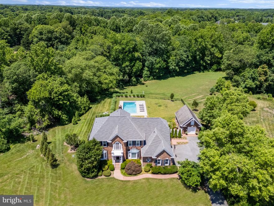 Experience Luxury Living in Cottage Farm Estates! Nestled in the heart of the prestigious Cottage Farm Estates community, this stunning all-brick colonial home with pool and spa sits on over 3 acres of beautiful sprawling grounds. As you approach down the tree-lined road, the grandeur of this residence becomes evident, promising an unparalleled lifestyle. Step inside to find a home that effortlessly blends elegance with functionality. The main floor welcomes you with formal living and dining rooms at the front, perfect for hosting intimate gatherings or grand celebrations. The heart of the home reveals an open floor plan where the family room with soaring ceilings seamlessly connects to a spacious gourmet kitchen and a cozy breakfast nook, making it the ideal space for everyday living. A charming library/office space provides a tranquil spot for work or relaxation, while a convenient powder room and a spacious laundry room add to the home's practicality. Ascend to the upper level, where you'll discover a serene and spacious primary bedroom with  ensuite, a true retreat at the end of the day. An additional ensuite bedroom provides privacy for guests, while two more large bedrooms share a well-appointed bath, ensuring comfort for everyone. The lower level of this home is designed for entertainment and fun.  The large open room with backyard access and a bedroom with adjacent full bath offers flexible living arrangements, perfect for extended family or visitors. Outside, the property continues to impress. A huge rear deck overlooks the stunning inground pool with an integrated spa. automatic cover and expansive pool deck, creating an inviting space for outdoor gatherings. The fenced yard backing to woods ensures privacy, making it a secure haven for relaxation. Additional features include a 3-car attached garage and a converted garage with a full bath and living space, complete with an unfinished attic ready for your personal touch. This versatile space can be tailored to meet your family's unique needs. This home is more than just a place to live; it's a private oasis where you can unwind, and enjoy life to the fullest. Don't miss the opportunity to make this extraordinary property your own. Welcome Home!