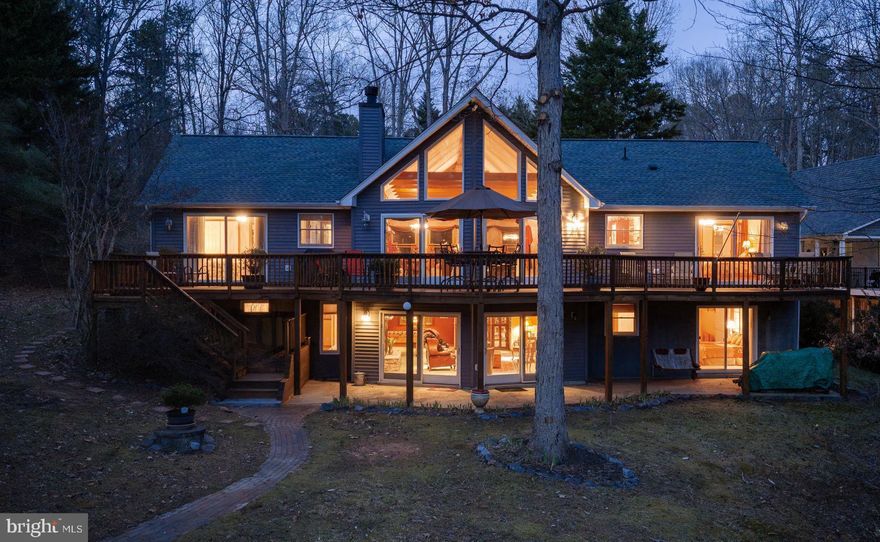 Enjoy true lake living at this beautiful waterfront retreat on the public side of Lake Anna. Tucked inside a quiet no-wake cove, you’ll love the peaceful setting, gorgeous lake views, and one of the best locations on the southern end of the lake — known for clearer water and easy access to wide open boating. Situated on 1.09 acres, this spacious home offers 3,282 square feet with 6 bedrooms, 3 full baths, and a comfortable open floor plan that’s perfect for gathering with family and friends. High speed Xfinity Comcast internet and the home comes furnished, so you can enjoy it right away! The main level features a warm and inviting family room with a stone gas fireplace, a wall of glass overlooking the lake, and vaulted beam ceilings that flows right into the kitchen, complete with stainless steel appliances and a breakfast bar for casual seating.
The lakeside primary suite has a corner soaking tub, walk-in closet, and sliding doors that open to the deck overlooking the water — a perfect spot to start or end your day. Downstairs, the lower level provides even more space with an additional family room featuring a wood-burning fireplace, three bedrooms, a full bath, and a utility room. Outdoor living is where this property truly shines. Enjoy a private sandy beach, approximately 100 feet of shoreline,  a lakeside patio, fire pit, and a covered boathouse with an electric lift, sundeck, sliding board with running water, and storage room — everything you need for fun days on the lake. You’re also just a quick 2-minute boat ride to Pleasants Landing Marina and El Gran Patron, making it easy to grab fuel, enjoy waterfront dining, or sip a margarita by the water. This is an ideal lake home for making memories — peaceful, spacious, and perfectly located for enjoying everything Lake Anna has to offer. New roof February 2022 and septic pumped in 2025.