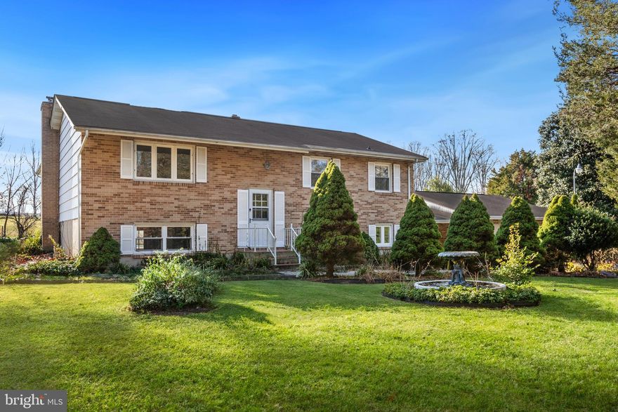 Find comfort and tranquility in this charming brick front 4 bedroom, 2.5 bath split-level home offering 2,700 SF of living space with potential for in-law living with a second full kitchen. The 2-story foyer entry leads you up to the main level living and dining rooms with crown molding and kitchen with passthrough window to the sunroom, ample storage and counter space. French doors to the large sunroom addition with hardwood floors and vaulted ceiling, natural light fills the room from the surrounding windows, perfect for enjoying the neighboring horse farm as you have your morning coffee. Down the hall you will find the full hall bathroom with double vanity, two bedrooms and a large primary bedroom. The lower level provides additional living and entertaining space with over 1200 SF including a cozy family room featuring a stone fireplace with wood stove insert, bedroom with full bath, half bath and a huge second kitchen. Potential in-law living with privacy as there are two additional ways to access with a door from the bedroom to the rear yard and door from kitchen to breezeway which attaches the home to the oversized 2-car garage. This home has it all with its spacious living to its peaceful backdrop of a farm in  the rear yard.