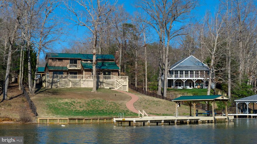 Welcome to life on the water at 13608 Elnora Brooks Ln in Spotsylvania County—a place where every day feels like a getaway at beautiful Lake Anna.

If you’ve been searching for space, privacy, and true waterfront living, this property delivers. Set on 2.43 acres, this 3-bedroom, 2-bath home gives you room to spread out, relax, and enjoy the outdoors in every season.

Step outside and take in one of the best features—an expansive deck overlooking Lake Anna, perfect for morning coffee, weekend cookouts, or quiet evenings by the water. Each bedroom has access to its own porch facing the lake, so you can wake up to peaceful views and fresh air every day.

Down by the shoreline, your private dock with a deep water slip makes boating, fishing, and swimming easy and fun. Located on Pigeon Cove directly across from Lake Anna State Park, you’ll enjoy scenic views and a calm setting while still being close to recreation.

Inside, the home is warm and inviting, with a wood-burning fireplace that creates a cozy place to gather. The layout offers flexibility, including an upstairs bedroom with an attached office area—ideal for working from home or creating a private retreat. There’s also a side room currently used as a gym, giving you even more space to fit your lifestyle.

Outside, this property truly stands apart. In addition to the home, you’ll find an oversized detached garage with unfinished space above—ready for a future office, studio, or guest area—with decks on both sides. The glass garage doors also turn this space into a great place to host gatherings, no matter what the weather is like. The garage doors are tall, offering plenty of room for boats, trucks, or a functioning garage workshop. There's also a large pole barn on the property, which provides excellent storage for equipment, tools, or even animals. With no HOA restrictions and short-term rentals allowed, you have the freedom to use this property in whatever way works best for you.

Whether you're looking for a full-time residence, a weekend retreat, or an investment opportunity, this Lake Anna property offers the space, flexibility, and waterfront lifestyle you’ve been waiting for.

Homes like this don’t come along often—schedule your private showing today and experience lake living for yourself.