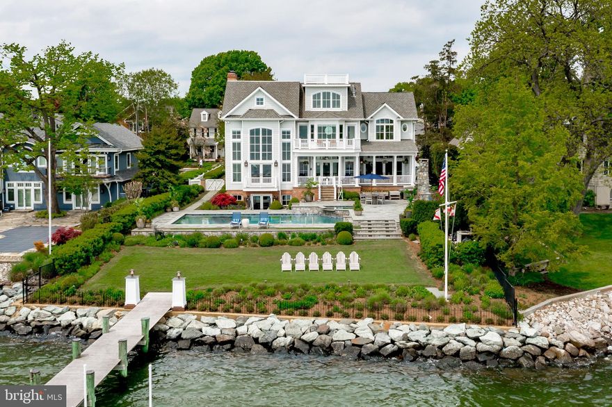 Nantucket meets Newport in this elegant, waterfront, Eastport home. Unparalleled views of The Chesapeake Bay, The Severn River and Back Creek.  The highest level of attention has gone into preserving and improving the character of this gorgeous, traditional home through exceptional upgrades with Pyramid Builders.  Four finished levels with 9000 square feet, Plus a "Widow's Walk" for Prime Blue Angels and Fireworks viewing. There are Multiple entertainment areas outside: on the water-side porches, the blue-stone pool deck, around the outdoor fireplace, in the hot tub and heated/cooled pool, taking in sunrises and sunsets in Adirondack chairs on the waterfront lawn, or at the tip of the IPE hardwood pier - next to your two boat lifts. This home has a flexible vibe - comfortable for intimate groups, or large-scale entertaining.  The interior is just as stunning and elegant as the exterior!  Light-filled rooms with High-End "Fit & Finish" rules the day! Unlimited water views and a parade of elegant boats coming and going from Back Creek will make you stop and take a second look in every water-side room.  The graceful living room with a marble surround fireplace with custom wood mantel, wet bar, vaulted ceiling and custom wood beams, or the equally sophisticated family room with coffered ceilings and a double-sided gas fireplace, or the dining room with a back-lit tray ceiling framed by columns and custom cabinetry. The open floor-plan includes the gourmet kitchen has updated high-end appliances, custom cabinetry painted with high-gloss, Fine Paints of Europe and solid brass handles.  The kitchen table space is warmed by the double-sided fireplace glistening views of the water.  Outdoor dining is just steps away on the main level overlooking the pool and views. The lower level offers easy access to the pool, with two updated, full baths. Every detail is addressed, down to the pool-towel cubbies in the shower room with an elegant glass shower. The fifth bedroom is an "Oh Wow!" Bunk Room with en suite bath that your visitors will be claiming as their own! Lower level also offers a Home Theater, Wine Room with 3 SubZero Wine Refrigerators, a Second Kitchen, Game Room Space and a second set of stairs to the kitchen. There are so many features to list, but here are a few stand-out features that take this home to the top of the list: Walnut flooring and rails, Elegantly incorporated over-sized Elevator with custom trim and glass doors, Custom Shutters, Solid wood doors with solid brass hinges & handles, Tray ceilings with back-lighting, Transom windows above the water-side windows and doors, Four fire places, Whole-House Security, Built-in AV capability, custom Lutron whole-house lighting system, Custom stair runner, Generously sized Couples' Dressing Rooms, Cedar Closet, Whole House Generator, Craft and Storage Room with SubZero catering fridge, Two Laundry Rooms and more.  Impeccably designed and managed landscaping by Walnut Hill.  No Flood Insurance Required. All systems in this home can be controlled remotely via Apps, for lock-and-leave enjoyment and peace of mind. The friendly white picket fence draws you inside to a home that has unlimited beauty, quality, elegance and the best views in downtown Annapolis!