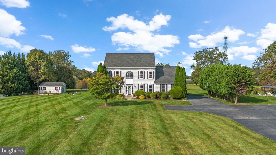 A long driveway leads to beautifully manicured landscaping and an elegant Colonial residence set within the prestigious Estates at Sand Hill, offering picturesque pastoral scenery with peaceful views of open fields and grazing farm animals. Step inside the bright, sun-filled interior where natural light pours through every room of the traditional layout. The welcoming foyer with gleaming hardwood floors leads to a convenient powder room, and double doors open to a quiet home office or study. Opposite the foyer, soft carpet flows throughout the formal living and dining rooms—graciously framed by elegant columns. The spacious family room impresses with soaring vaulted ceilings and a cozy wood-burning fireplace, creating a perfect space for relaxing or entertaining. The stunning, bright white, eat-in kitchen serves as the heart of the home, featuring gleaming hardwood floors, quartz countertops (2025), stainless steel appliances, including a refrigerator updated in 2022, an island with breakfast bar seating and pendant lighting, a built-in writing station, and a cozy breakfast nook with access to the patio. Nearby, the laundry room (washer and dryer updated in 2022) offers garage access and a convenient drop zone with hooks for coats, bags, and everyday essentials.

Upstairs are four comfortable and carpeted bedrooms and two full bathrooms. The spacious owner’s suite showcases vaulted ceilings, a large walk-in closet, and a spa-like ensuite bath with a dual-sink vanity, a separate water closet, and a luxurious corner soaking tub. One of the secondary bedrooms adds charm with a stylish coffered accent wall. The walk-up lower level offers a generous wraparound recreation room with flexible areas for entertaining, lounging, or hobbies, along with a large storage room. The home also features a well-maintained garage—complete with finished walls, epoxy flooring, and an electric car charging port for added convenience. Outdoors, enjoy the beautifully landscaped setting with a patio surrounded by lush greenery, a large flat backyard with rear fencing, a fire pit area, a storage shed, and garden beds—all backing to scenic farmland for a serene countryside backdrop.