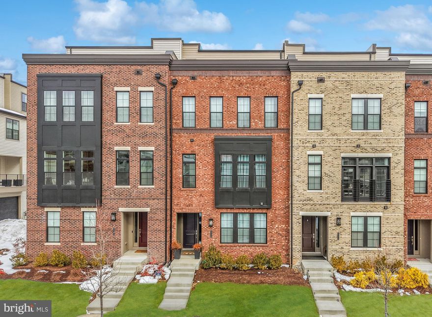 Immaculate luxury, move-in-ready four level townhome-style residence located in the highly desirable Metro Walk at Moorefield Station, just steps from the Silver Line Ashburn Metro Station. Offering over 3,000 square feet, spacious 4 bedrooms, 3 full bathrooms, 2 half bathrooms, and a 2-car garage, this home combines elevated design, thoughtful upgrades, and exceptional access to everything Ashburn and Loudoun County have to offer.

(Entry & Lower Level) From the front door, you’re welcomed into a bright and versatile lower level finished with upgraded luxury vinyl plank flooring and connected by hardwood stairs throughout. This level includes a dedicated office nook, ideal for working from home or managing everyday life, along with a generously sized ground level bedroom and full bathroom, with a walk-in closet, perfect for guests, a media room, gym, or private retreat. Direct access to the 2-car garage with upgraded epoxy flooring adds both convenience and a polished, high-end finish.

(Main Living Level) As you move up to the main living level, the home opens into a spacious, light-filled layout designed for both everyday living and entertaining. 10ft ceilings and upgraded luxury vinyl plank flooring throughout enhance the open feel, while the inviting great room flows seamlessly into the dining area and kitchen. The chef’s kitchen anchors this level and features upgraded Silestone Miami Vena quartz countertops, an upgraded full quartz backsplash, and an abundance of upgraded Century cabinetry with enhanced hardware. Cooking and entertaining are elevated with an upgraded gas cooktop, premium KitchenAid stainless steel appliances, and upgraded matte black fixtures, all thoughtfully selected for both style and performance. Adjacent living spaces open naturally to outdoor areas, with gas line rough-ins at both the fourth-level terrace and the double-door entry patio, making future grilling and entertaining effortless. 

(Bedroom Level) Continuing upward, the bedrooms level offers privacy and flexibility, including a spacious second and third bedroom with a full hall bath, near the laundry closet. These generous rooms are ideal for guests or multigenerational living. Bathrooms on this level showcase upgraded finishes, including quartz countertops, upgraded dual vanities, and designer tile selections. Both the primary bathroom and the hall full bathroom on the third level feature separate toilet rooms, adding everyday convenience and privacy. The primary suite serves as a true retreat, complete with a spa-inspired bath featuring upgraded primary bathroom tile, a fully large, tiled shower, refined hardware, and upgraded fixtures designed to create a calming, luxurious experience. 

(Fourth Level & Outdoor Living) The home continues to impress on the fourth level, finished with upgraded luxury vinyl plank flooring and designed for entertaining and relaxation. This level features a half bathroom, a large flex space, and a wet bar, counter space with refrigerated beverage center, opening to both covered and uncovered terraces, ideal for hosting guests, enjoying morning coffee, or taking in seasonal views.

(Community & Location) Residents enjoy access to Westmoore, a premiere neighborhood known for its exceptional amenities, including two large parks with open green spaces, two playgrounds, an amphitheater, dog park, pavilion, clubhouse, community pool, and fitness center. Conveniently located near Broadlands Marketplace, Loudoun Station, and everyday conveniences, this home also offers quick and easy access to the Dulles Greenway, Route 7, Route 28, One Loudoun, and Dulles International Airport. With the Silver Line Ashburn Metro Station just steps away, commuting and travel are seamless.

This exceptional home delivers upgraded finishes on every level, flexible living spaces, premier community amenities, and one of the most connected locations in Loudoun County, a rare opportunity to own luxury living at its finest.