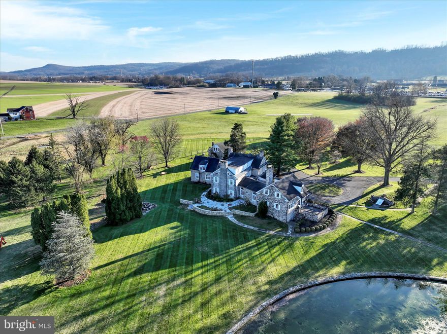 The splendid property known as Big Spring Farm, situated in Western Berks County, boasts an intriguing history that dates back to 1730, when William Allen, a wealthy merchant from Philadelphia, first conveyed the land. It is thought that the Allen family erected the two stone residences overlooking the picturesque 1-acre pond for their summer getaways. The political upheaval that followed the signing of the Declaration of Independence in 1776 eventually led to the Allens losing ownership of the estate due to the Divesting Act. Over time, various owners cultivated the land, but in the 1960s, Dr. Frederic B. Thomson, a local veterinarian, established an equine hospital on the property, focusing on thoroughbred care. The estate, named Big Spring Farm, is renowned for its spring-fed pond, which is considered to be the largest spring water aquifer of its kind east of the Mississippi. It is one of Berks County's most exquisite estates. The entrance to the farm is marked by a 1-bay garage size gatehouse. Stately century-old maples line the driveway, which leads to the primary entrance, service entrance, and a 3-bay carriage house featuring an apartment. The property spans 23.6 acres, with a considerable portion being fenced pastureland. Gentle slopes surround the 1-acre pond, and flagstone pathways lead to various outdoor features, such as Al Fresco terraces, an enchanting octagonal gazebo, a root cellar, and a stone spring house. The dock gazebo by the pond provides a romantic setting for evening gatherings.
The main residence, a stunning over 6,300 square-foot structure, combines colonial elements from 1735 and 1740 with a beautiful 20th-century addition. The home's rich history is evident in its architectural details and original finish materials. Noteworthy features include the family room's fireplace, believed to have been salvaged from the original fire-damaged White House in Philadelphia, as well as striking fireplaces in the living room and formal dining room. The thick stone exterior walls of the home create substantial 24' interior window sills, perfect for displaying indoor plants or collectibles. The home's unique layout offers numerous possibilities for room utilization, making it ideal for hosting holiday gatherings, accommodating seasonal guests, and conducting grand formal events with its 18 rooms and 6 1/2 baths.