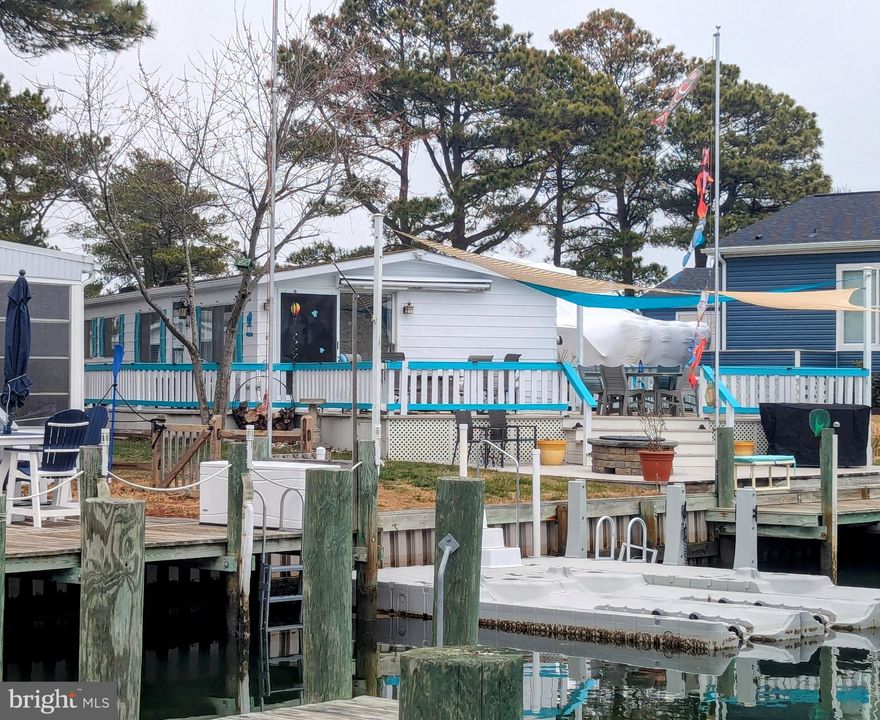 Waterfront home with private boat dock now available in Pot-Nets Seaside!  This charming and well maintained home will delight you every step of the way!  This is a doublewide home with three bedrooms, one full and one half bath, Living Room with view of the canal includes a cozy gas fireplace with mantle and raised hearth.  The Dining Room and Kitchen are large enough for family and friends to gather, the bedrooms are good size and this is a turn key home with all interior furniture included! The furnace and Air conditioning unit were replace three years ago and everything is in great working condition. Best of all, there is a 500 square foot upper rear deck and a large lower deck with a firepit, and the private 25 ft boat dock is just a step down from the lower deck and an outside shower with privacy surround! This is a rare opportunity to have your boat right in your back yard all season long!  Pot-Nets Seaside is a beautiful waterfront community with a gorgeous private sandy beach, in ground swimming pool,  dog park, playgrounds, golf car paths, several boat marinas and the Seaside Grill offering great dining and live music in the summer months. Lot rent is $1607 per month which includes the boat dock and trash/recycle pick up. The jet ski dock is negotiable.