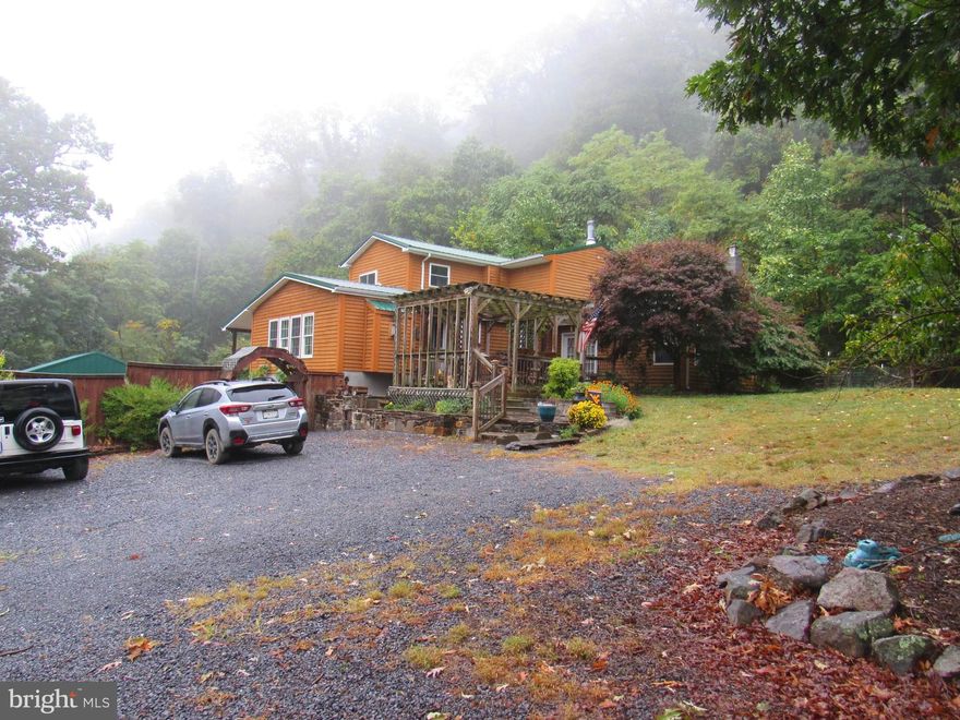 Enjoy the peace and quiet of country living in this spacious 2900 SF 3BR 3.5BA home on 5.57 acres in quiet subdivision near Wardensville.  Large living room with a gas fireplace and cathedral ceiling, Kitchen has granite countertops and separate pantry, and a separate dining area, both with their own fireplaces .  The main floor also has a bedroom with doors onto the deck which could easy be converted to a family room.  Bonus room could serve as a  office or small bedroom.  Laundry is  conveniently located on the main floor and includes new stacked washer/dryer.   Upstairs the primary bedroom has it's own bath, and a walk in closet.  The upstairs guest room also has it's own bathroom.  There's another deck out back with a patio that includes a seating area, covered stainless steel outside kitchen area, bar, firepit and water feature.  There's also a greenhouse, chicken coop and small garden area  where you can pick your own plums off of the plum trees or gather blueberries from the garden.    The three car garage is a handyman's dream with 2 heated storage rooms on one end, running water and another large enclosed area with stone floor, shower hook up and a chimenea on the other side.