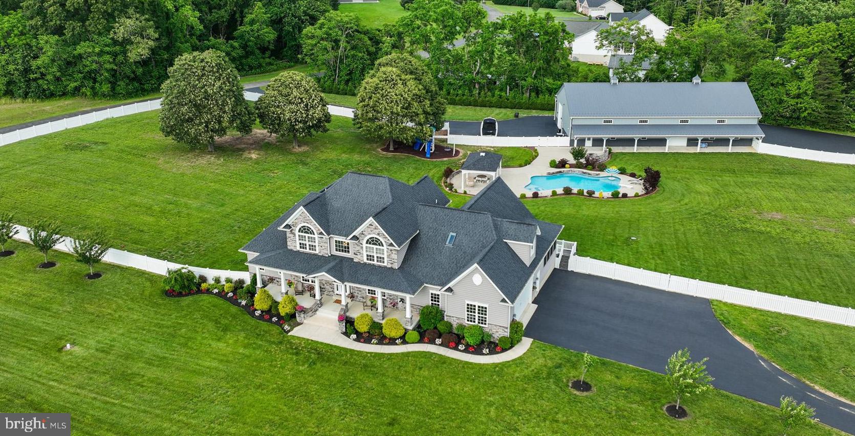 Welcome to your dream estate! Nestled on a picturesque 4.67-acre lot, this stunning property offers luxury living inside and out. Enjoy resort-style amenities with a 40-foot Gunite, heated, saltwater pool featuring waterfalls, a tanning ledge, a diving board and a built-in table and lounge — perfect for relaxing or entertaining. the newly added poolside pavilion provides shaded comfort! The massive 96x48 pole barn is a showstopper, equipped with a commercial 5-ton central HVAC heat pump system, spray foam and blown attic insulation, 16-foot ceilings, three 14-foot commercial bay doors with openers, and a 7'x8' porch-access door also equipped with an opener. The finished 20x42 loft features home-grade railings & stairs and is ideal for a studio, office, or recreation space. The barn also includes front and back lean-tos (10' and 12') and its own 250-amp electrical service. The home spans over 6,200 square feet with 3,969 sq ft above grade and 1,116 sq ft below. The main level offers exceptional living spaces, including two family rooms, a gourmet kitchen with a center island, stainless steel appliances, granite countertops, and a pantry, a professional den, a formal dining room, and a luxurious primary suite with a spa-like bathroom and walk-in closet. Upstairs, you’ll discover four generously sized secondary bedrooms along with two full bathrooms. The fully finished lower level is a must-see, showcasing a custom bar, a recreational room with a stone fireplace, a full bathroom, and a spacious gym. Don’t overlook additional amenities, such as an all-season porch, multiple fireplaces, a covered rear porch, a fully fenced rear yard, professional landscaping and much, much more! This sale also includes an additional 1.25-acre open space lot. This exceptional property combines privacy, space, and unparalleled amenities — truly a rare find!