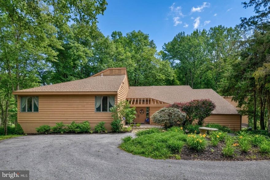 Nestled deep within a lush, wooded landscape, this stunning contemporary retreat offers the perfect blend of architectural character and natural serenity. Designed to bring the outdoors in, this exceptional four-bedroom, 2.1-bath custom home is perfectly situated on 5.73 private acres within the prestigious Unionville-Chadds Ford School District. Located on a quiet cul-de-sac in Delaware County, the property offers a lush, nature lover's entrance that leads into an inviting foyer with hardwood floors and soaring vaulted ceilings. The main level features a sunken living room anchored by a wood-burning fireplace and a wet bar, flowing effortlessly into a sun-drenched dining room. At the heart of the home, the kitchen boasts a center island, stainless steel appliances, and ample cabinetry, overlooking a morning room that transitions into a cozy family room with its own vaulted ceilings. Two separate entrances lead to a show-stopping sunroom, providing breathtaking views of the grounds and access to a wraparound deck that spans the length of the main living areas. The first-floor primary suite serves as a true retreat, offering vaulted ceilings, built-in walk-in closets, and a main bathroom equipped with a double vanity and jetted soaking tub. Upstairs, you will find three additional well-sized bedrooms and a full bathroom. The expansive acreage creates a private paradise complete with heavy landscaping and a peaceful creek at the base of the grounds, all while maintaining convenient access to major highways like Route 202 and Route 1. This is a rare opportunity to own a home that truly transcends the ordinary.