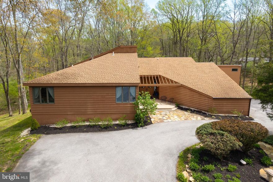 Nestled deep within a lush, wooded landscape, this stunning contemporary retreat offers the perfect blend of architectural character and natural serenity. Designed to bring the outdoors in, this exceptional four-bedroom, 2.1-bath custom home is perfectly situated on 5.73 private acres within the prestigious Unionville-Chadds Ford School District. Located on a quiet cul-de-sac in Delaware County, the property offers a lush, nature lover's entrance that leads into an inviting foyer with hardwood floors and soaring vaulted ceilings. The main level features a sunken living room anchored by a wood-burning fireplace and a wet bar, flowing effortlessly into a sun-drenched dining room. At the heart of the home, the kitchen boasts a center island, stainless steel appliances, and ample cabinetry, overlooking a morning room that transitions into a cozy family room with its own vaulted ceilings. Two separate entrances lead to a show-stopping sunroom, providing breathtaking views of the grounds and access to a wraparound deck that spans the length of the main living areas. The first-floor primary suite serves as a true retreat, offering vaulted ceilings, built-in walk-in closets, and a main bathroom equipped with a double vanity and jetted soaking tub. Upstairs, you will find three additional well-sized bedrooms and a full bathroom. The expansive acreage creates a private paradise complete with heavy landscaping and a peaceful creek at the base of the grounds, all while maintaining convenient access to major highways like Route 202 and Route 1. This is a rare opportunity to own a home that truly transcends the ordinary.