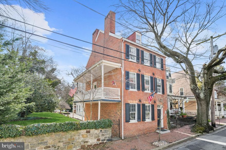 Stately Federal style circa 1830 home situated in the heart of the treasured Historic District of Downtown Annapolis. Experience the joys of being steps to the City Dock amongst the restaurants, specialty shopping, art galleries, music venues, lively Main Street, and local events of Maryland’s capital. Historically significant, the property has served over the years as a private residence and popular bed & breakfast. The four-story building was last renovated in 1996, yet the architectural integrity and 19th century ambiance were authentically preserved. A magnificent property in every way, the home features characteristic double parlors of the Victorian era, original random-width hardwood flooring, double staircases providing owner privacy, classic chair rail, custom built-ins, Greek Revival mantels on several of its six fireplaces, and the last remaining Charleston piazza in Annapolis that affords owner privacy exiting/entering the house. The main level features a welcoming foyer with double chair rail, two formal parlors with elegant fireplaces, and a formal dining room. The updated kitchen is appointed with granite counters, stainless steel appliances including a Viking 6-burner range, and breakfast bar. Further is a brick-floored room of varied potential uses including a workshop, seasonal conservatory, or studio.  The upper levels host a collection of five bedrooms, each with distinct charm and character, and four full baths with either a jetted soaking tub with hand shower or clawfoot tub/shower with designer marble and other attractive finishes, as well as owner spaces and amenities that can be made separate, if desired. The first upper level hosts a den and office with ample closet storage space. Additionally, the first upper level offers two bedrooms, each with a cozy fireplace and en-suite bath, and one features access to the 141 sqft piazza overlooking the beautiful yard. Connecting bedrooms have the potential to be converted into a large primary suite. The second upper level provides three additional bedrooms, including the primary with rooftop deck access, two full baths, two fireplaces, laundry room, and cedar closet. The finished fourth floor provides additional living space to suit any lifestyle need. Step outside for a relaxing afternoon reading a book or entertaining guests in the spacious yard adorned with a brick patio, mature shade trees, and colorful blooms with total privacy rarely found in downtown locations. This incredible property sets the stage for the quintessential Annapolitan lifestyle just steps all that Annapolis has to offer!