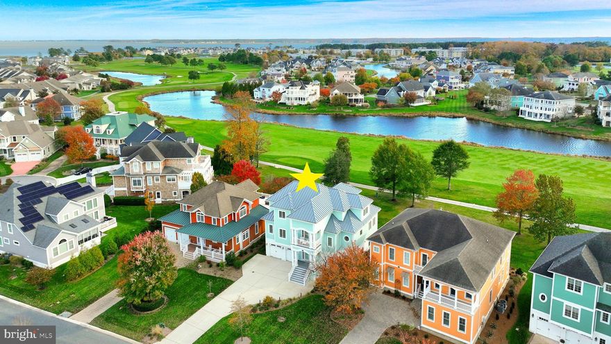 Experience this original Echelon custom-built model home in the amenity-rich resort community of The Peninsula, where pond and golf course views create a serene backdrop for everyday living. Meticulously maintained, this residence offers sophisticated style that is masterfully crafted and impeccably appointed. Recent upgrades further enhance its appeal, including exterior painting (2025), new gutters and downspouts (2024), a new driveway (2023), updated landscaping and exterior lighting (2023), a water softener and filtration system (2022), security alarm and cameras (2022), smart thermostat (2022), and smart TV with surround sound (2022), all contributing to a modern and secure living experience.

The home emanates coastal charm throughout, with a bright and easy-flowing floor plan that showcases a two-story great room bathed in light from soaring stacked windows, seamlessly inviting the outdoors into the living space. An entertainer’s dream gourmet kitchen features an expansive center island, granite countertops, 42” custom display cabinetry, breakfast bar, walk-in pantry, a Monogram oven, and a suite of stainless-steel appliances to inspire your inner chef.

Refined details define every corner of this home, from its decorative paneling and moldings to the classic square columns with arches, custom built-ins, fireplace, and gleaming hardwood floors spanning all three levels. The dining area, wrapped in windows and adorned with a stylish chandelier, is perfect for hosting intimate dinner parties with views of nature. Two graciously sized bedrooms, one with an en suite bath, and an additional full bath complete this level.

Retreat via the staircase or elevator to the spectacular primary suite, where generous proportions include a sitting area, plush carpeting, and French doors leading to a private balcony. Indulge in the spa-inspired en suite bath boasting a soaking tub, oversized shower with seating, dual vanities, custom lighting, and a sizable walk-in closet with window and custom built-ins for wardrobe organization.

The lower level delivers another spacious bedroom, a full bath, and a second family room with an entertainment area, custom bar with granite countertop, beverage fridge, and wine storage. French doors open to the covered patio—just one of several outdoor living spaces to enjoy your morning coffee or an afternoon drink while taking in breathtaking vistas of The Peninsula on the Indian River Bay. From the main deck, watch golfers tee off on the 11th hole of the Jack Nicklaus Signature Course and be reminded why you chose this extraordinary home!  Schedule your private tour today and experience firsthand what makes this remarkable home one of the finest in the community.