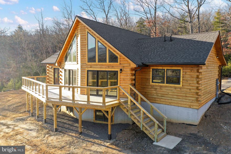 JUST COMPLETED!  Final Touches &  landscaping are all that are left to wrap up!  Nestled amidst the picturesque mountains of West Virginia, this custom-built log home, completed in 2023, is a masterpiece of architectural design and natural beauty. Boasting ample square footage, the residence provides a spacious and inviting atmosphere that perfectly complements its stunning surroundings.  The home's large windows on both levels frame panoramic mountain views, allowing residents to bask in the beauty of the changing seasons. An expansive deck extends from the rear, offering an ideal spot for outdoor entertainment while overlooking the iconic Appalachia Mountain range.  Located in close proximity to the charming village of Wardensville, residents have easy access to local markets, fine dining establishments, and shopping venues. For outdoor enthusiasts, the nearby national forest provides a plethora of activities, including river access, hiking trails, skiing opportunities, and prime public hunting grounds.  Bring your lawn chair to the family run, organic farm across the road and enjoy a summer evening of bluegrass music, dancing, and enjoyment!  Constructed with pine throughout, the interior exudes warmth and rustic charm.   Beautifully crafted live edge seating area and coffee bar are just a few of the custom features of this gorgeous home.  Vaulted ceilings and exposed beams add to the home's character, while smart spaces maximize functionality. The residence features large bedrooms, including an enormous loft area perfect as a spacious office or additional bedroom.  One of the notable amenities is the excellent high-speed fiber optic internet service, ensuring connectivity for remote work or leisure. The property is conveniently located under two hours from Washington DC, making it an accessible retreat. The community, characterized by its tranquility, adheres to sensible covenants and restrictions, with well-maintained roads ensuring year-round access.  Short term rentals are permitted which opens the opportunity for this beautiful home to have investment potential as well!  For those seeking the perfect blend of luxury, natural beauty, and outdoor adventure, this West Virginia Mountain retreat promises an idyllic lifestyle in a quiet and welcoming community.