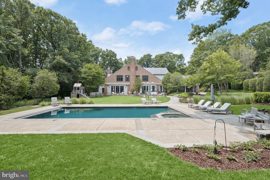 Located in one of the Capital Region’s premier residential communities, with distinguished estate homes occupying its sprawling wooded lots dotting its wide, winding streets, this singular estate in Potomac Village stands alone. Within this rarified air, 10105 Iron Gate Road is sited on 2.04 private, spectacular acres. Evoking cues from the summer homes of Nantucket yet retaining the distinctive solidity of a colonial, the estate was originally custom built by Peterson & Collins, a longstanding Washingtonian firm constantly at the forefront of global residential construction and design. Such a reputation is evident in the architectural details of the home, beginning with an elegantly curved covered porch facing towering mature trees. Inside, an intimate vestibule opens into the grand foyer, bound by the sweeping staircase and upper level mezzanine overhead and around which all rooms revolve. Embassy sized formal living and dining rooms flank the space in a nod to a more traditional center hall layout. The former boasts a gracious curved wall of windows with verdant views, while the latter features a hidden butler’s pantry enabling effortless flow. Informal areas span the entire rear of the main level, anchored by the chef’s kitchen. A SubZero/Wolf appliance suite, natural stone countertops, extensive cabinetry, and coffered ceiling define the space. The adjacent breakfast area offers patio access and wooded views, while the adjoining keeping room features a cozy gas fireplace. A connected mudroom with laundry facilities, a full pool bath, and access to the attached three car garage greatly augments functionality. A large, natural lit family room with fireplace, built-in wet bar, and direct patio access completes the main level. The upper level primary suite’s expansive sitting room and more intimate barrel-ceilinged sleeping area effectively creates two different zones while maintaining an unbroken open space. The newly-renovated primary bath is clad in white marble, featuring all of the ubiquitous accouterments – separate vanities, walk-in shower, freestanding tub – and opens into an aspirational dressing room with extensive built-ins and center island. Five secondary bedrooms, one ensuite and two pairs of jack-and-jills, revolve around a common sitting area on this level. The top level features an additional bedroom suite – ideal for a teenager, yoga studio, hidden retreat, or private office. A large recreation room bisects the entire width of the lower level – a full 57½ feet. A wine cellar, two bedrooms, two full baths, and an exercise room completes the space. Out back, the rear lawn is a showstopper. Level, usable, and bound by mature foliage, there is ample room for a sports court. An extensive flagstone patio cascades into the heated pool and spa with automatic cover, newly renovated by Alpine Pool and Spa. Whimsical hardscaping, landscaping, and up-lighting after the sun sets establish a complete, private, natural oasis. Behind the scenes, commercial-grade systems such as new HVAC, a new driveway with future gate wiring, and a state-of-the-art surround sound system including outdoor speakers facilitates peace-of-mind contemporary living. Lavishly equipped, generous in scale inside and out, and situated on an incomparable lot within a central Potomac location, 10105 Iron Gate Road is a preeminent estate for the most discerning buyer.