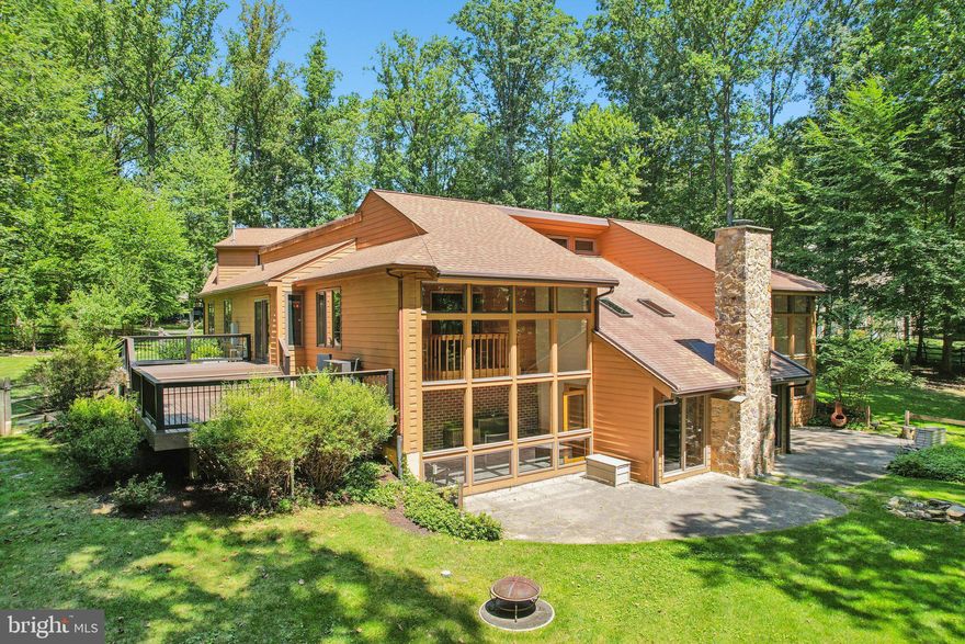 Tucked away on a private and serene 1.6-acre wooded lot, this charming single-family home offers a rare opportunity to enjoy peaceful living just minutes from downtown Exton. Set back 500 feet from the road on a flag lot, the property provides a quiet retreat while still being conveniently close to everything. Upon entry, you're welcomed into a foyer with a vaulted ceiling that offers a striking view overlooking the spacious family room. The heart of the home is the stunning lower level family room, enhanced with a tucked away wet bar and two sets of sliding doors on either side of the beautifully redone stone-faced, wood-burning fireplace, offering seamless access to the back patio and yard. Several skylights overhead flood the space with natural light, creating an inviting atmosphere year-round. Enjoy even more sunlight in the two rear sunrooms on either side of the family room, each featuring walls of windows that bring the outdoors in and balconies from upstairs. This level also includes two bedrooms, a full hall bath, a laundry room with storage, a dedicated home office, and a separate unfinished storage room. Back on the main level, a newer, modern eat-in kitchen with a center island and breakfast nook is perfect for everyday living and hosting guests. Sliders off the breakfast nook lead to a large side deck and off the kitchen is a formal dining room with a balcony overlooking one lower level sunroom. A spacious living room with built-ins and a refreshed half bath leads to a mudroom providing a second entrance to the driveway and access to the oversized three-car attached garage. Above the garage is a partially finished loft perfect for a workshop, art studio, or hobby room. On the other side of the main level, you'll find a spacious primary bedroom with a balcony overlooking the second lower level sunroom and ensuite bath with a dual vanity, walk-in shower, and window seat.  Recent upgrades include a newer public water line, updated sewage grinder pump tied into public sewer, a 14kW whole-house generator, replacement of all 32 rear windows, and fresh paint throughout. Just 5 minutes to the Exton train station and close to shopping, restaurants, and major highways, this home offers easy access to Center City Philadelphia, Lancaster, and even NYC via Amtrak. Don’t miss this unique blend of privacy, comfort, and convenience!