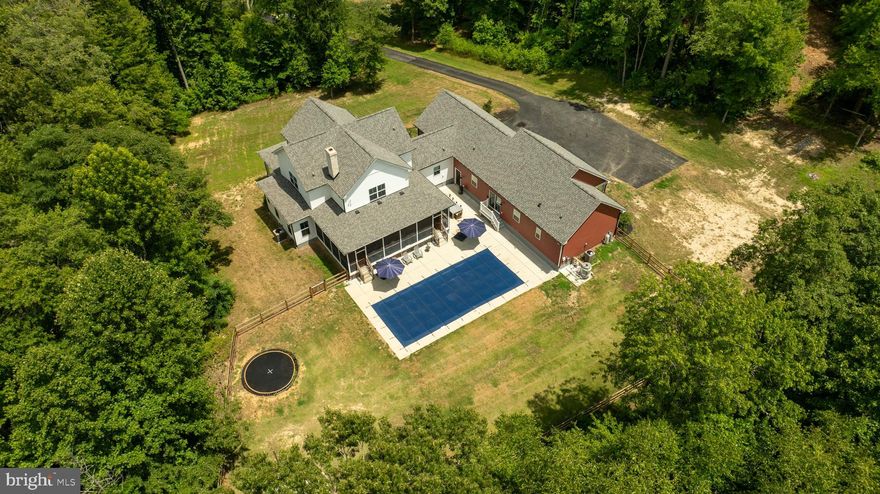 Discover unparalleled privacy and tranquility in this custom-built home, privately nestled within a lush pocket of trees off a secluded cul-de-sac. Situated on 3.6 acres of serene woodland, this residence offers the perfect escape from the hustle and bustle of everyday life. As you approach the main home, you're greeted by an expansive front porch with elegant brick trim—ideal for enjoying a morning coffee while immersed in nature. Enter through the garage into a well-designed mudroom featuring a built-in arrival center, designed to keep your daily essentials organized. Adjacent is a large laundry room for added convenience. The open-concept living area is the heart of the home, highlighted by beautiful wooden pillars that add a touch of rustic elegance. The kitchen is a chef's dream, complete with a large island featuring a farmhouse sink, a custom-built wood range hood, and a secure walk-in pantry complete with its own access code. The inviting family room centers around a brick wood-burning fireplace flanked by custom built-ins, creating a warm and welcoming atmosphere. Down the hall, the primary bedroom is a private sanctuary with its own access to the screened-in back porch, a spacious walk-in closet, and a luxurious ensuite bathroom with a soaking tub, TV, and dual vanities. Additional features on the main level include a built-in desk under the stairs and a cozy reading nook / work area. Ascending the integrated illuminated hardwood stairs, you'll find a second-story family room with walk-in closet storage. This level also houses two large bedrooms that share a Jack & Jill bathroom and a spacious third bedroom with its own ensuite bathroom. The expansive screened-in porch, accessible from the family room through two sets of French doors, overlooks a fenced-in backyard oasis. Perfect for entertaining, this outdoor haven includes a TV, a saltwater pool with a pool chiller, an inground trampoline, and a firepit plus 2 year old fence. The attached in-law suite is a perfect blend of comfort and style, featuring a spacious front porch for relaxing. Inside, the family room is outfitted with built-ins that are roughed in and ready for a gas fireplace. The open-concept continues with a kitchen and dining area ideal for modern living. The primary bedroom offers a walk-in closet and an ensuite bathroom with a soaking tub. This in-law suite also includes a bonus room for use as an office or den, its own laundry room, and direct access to the shared garage and backyard oasis. This stunning property is conveniently located just 15 minutes from Fairview Beach to the east and downtown Fredericksburg to the west, offering both peaceful seclusion and easy access to amenities. Experience the perfect blend of luxury, privacy, and natural beauty in this exceptional home, your personal sanctuary amidst the trees.  Major income potential.