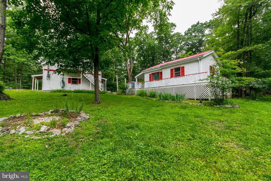 Cute cottage in the woods with lake access only 6 miles south of Berkeley Springs, WV.  Additional living space above garage with full bath.  Enjoy the quiet and peace from the wrap around deck.  Compact house means easy maintenance.  Enjoy fishing, swimming, and bring a picnic to enjoy the private lake. Two lots totaling 3.93 acres.
