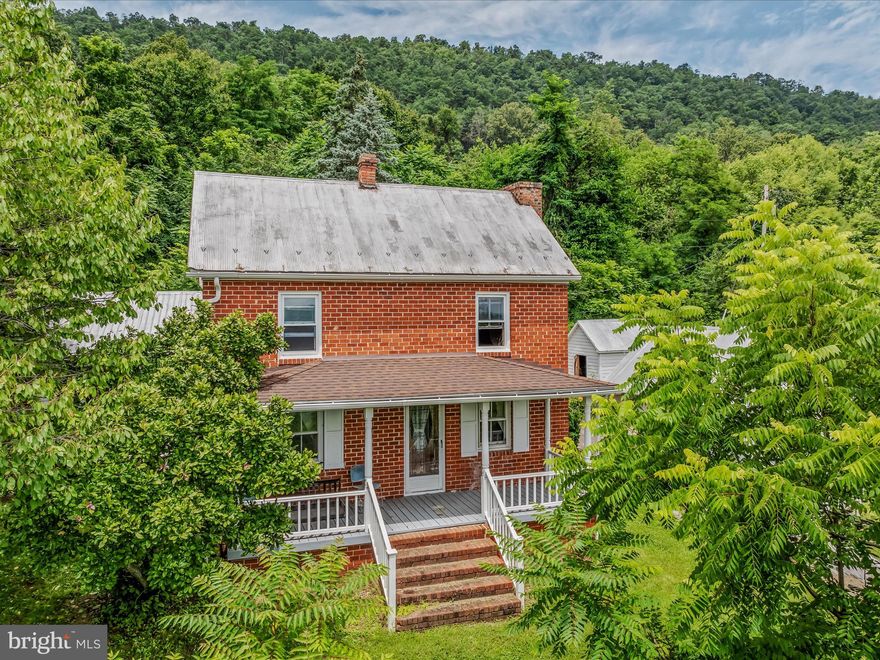 This classic all brick colonial is just what you think of when picturing a farmhouse. It features beautiful details you rarely see any more such at pine floors and a metal roof complete with snowbirds. The home sits on a large, 5.12 acre lot. The lot is made up of wooded area with mature trees for privacy and cleared area for enjoying the outdoors. From your lot you get the amazing mountain views West Virginia is known for. The home features a large, covered porch just waiting for your rocking chairs. Inside the home you have a mudroom with ceramic tile floors. Beyond that you have a spacious kitchen with vinyl floors and knotty pine cabinetry. The laundry room keeps your machines nicely tucked away. The kitchen opens to the large living room. This set up is great for entertaining. The living room includes ceiling fan, flue for wood-burning stove, and access to the rear patio. The spacious dining room features pine floors, built-ins, and wood-burning fireplace with Fisher insert. There is a nice office space with lots of natural light. The full bath has been updated with LVP floors and 3 ft acrylic tub and 4 ft single bowl vanity. Upstairs you have e3 spacious bedrooms with pine floors and large windows. Outside you have a covered side porch, perfect for taking in the views. There are 2 large storage sheds. One includes a loft and electric. You even have a lovely stone springhouse. This home has so much potential for you and your family. Come take a look today!