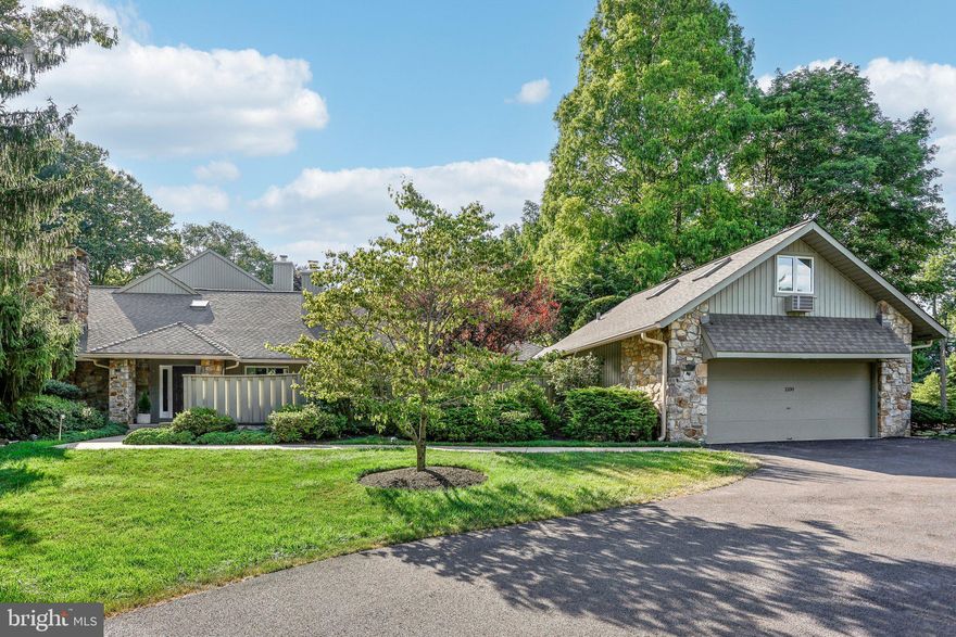 Welcome to 1100 Saint Andrews Road, a quiet and beautifully landscaped end unit in The Hermitage community.   This ranch-style home emanates an inviting warmth that greets you from the first step into the foyer entrance.  The unit is awash in natural light, radiating from in-set skylights and panoramic sliding glass doors in every direction.  Just off the foyer is a beautiful den with built-in cabinetry and recessed lighting, accentuated by a wood-burning fireplace.  Step down into the spacious living room with ample room for entertaining.  The verdant landscape architecture is in full-surround through sliding glass doors that provide access to the private patio areas and the marquee floor to ceiling stone fireplace acts as a visual centerpiece to all.  The eat-in kitchen boasts a Sub-Zero refrigerator, Thermador double oven, cooktop and generous granite counters with an open design that allows for quick access to pantry, laundry room and attic.
The primary suite boasts a large sitting area with built-in bookshelves, walk-in closets connecting to the sprawling main bathroom complete with a soaking tub, shower and double vanity.  The second and third bedrooms each have ample closet space and Jack and Jill bathroom and each with access to an outdoor walkway.
The oversized two car garage includes a breezeway to a versatile upstairs bonus room an half-bath, ready to actualize a multitude of uses; whether an exercise room, game room, extra bedroom or dedicated office with a mix of both natural light and recessed lighting.  The large attic area is renovation-ready, with trusses in place to accept any design vision or simply act as an easily accessible storage area. 
The open floor plan manages a seamless flow throughout the unit with an effortless marriage of interior luxuries and exterior natural beauty and privacy in what has always been one of the Main Line’s most coveted addresses.