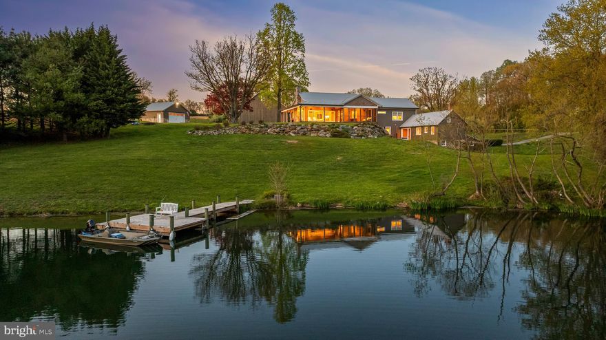 Welcome to "Hickory Farm" a charming property that offers a tranquil and picturesque setting nestled on just under 80 acres of rolling farmland, mature trees and abundant wildlife. As you enter through the gated property and drive down the long winding driveway you'll be greeted by the enchanting sight of a totally renovated contemporary farmhouse  with a wrap-around porch that seamlessly blends modern amenities with rustic charm. Upon entering the main level you'll be greeted by the spacious great room, kitchen and living area. The centerpiece of the room is the floor-to-ceiling stone fireplace and the abundance of windows which fills the room with natural light creating an atmosphere of warmth and comfort. This space is great for entertaining and offers spectacular views of the 3.5 acre pond. Also, on the main level is the primary bedroom suite with a side balcony for you to enjoy your morning coffee. The lower level has additional living space with the original stone foundation adding a rustic touch to the family room, bar and another bath and bedroom with a side porch. Step outside the lower level and you'll discover another 2 story structure. This space could provide a unique and versatile use such as a guest cottage or home office, just use your imagination and creative ideas. In addition to the house there are a few more outbuildings. There is a detached two car garage that has been transformed into a man's cave, complete with a mini-split system for climate control, so you can store farm equipment or extra room to hang out. The 66' x 42 post & beam bank barn with 5+ stalls offers the perfect opportunity for equestrian enthusiasts or housing small farm animals. There is also a small wood shed and the open pavilion by the house. The house uses geo thermal for HVAC and additional updates are the full house generator, significantly upgraded Cable, Internet and WiFi and security features such as surveillance cameras, alarm system, the remote controlled main gate. The pond has a new overflow drain, 4 diffuser aeration system and is completely stocked with small & large mouth bass. It is important to note that this property is protected by a conservation easement and participates in an agricultural land preservation program. This ensures that the land cannot be subdivided and has been maintained by the same farmer for many years, preserving its natural beauty and agricultural heritage. Overall, this property is a blend of historical charm, contemporary design and breathtaking surroundings offering a unique lifestyle to embrace a peaceful place to relax, connect with nature and rejuvenate.