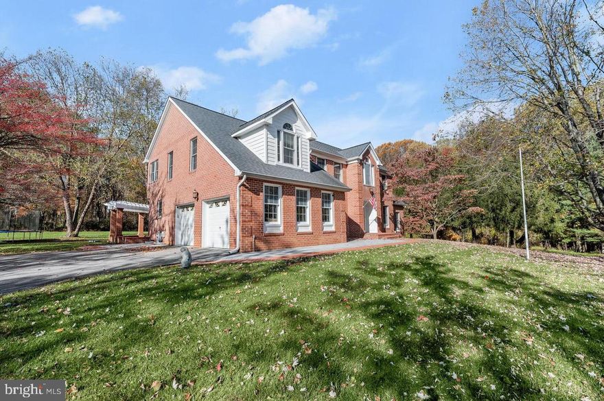 ***$25,000 PRICE REDUCTION*** Elegantly positioned on a sprawling 3.25 acre estate, this grand 4-bedroom colonial masterpiece of all-brick construction with over 5,000 square feet of living space is poised to captivate discerning buyers. Boasting 3.5 nicely appointed bathrooms, this remarkable residence offers a blend of luxurious living and expansive entertainment spaces. As you approach this stately abode, a long and meandering driveway welcomes you, offering ample space to accommodate more than a dozen vehicles. The property's floor plan is a seamless fusion of both social and tranquil spaces. A distinguished study provides an ideal home office sanctuary, while the generously proportioned sunroom can effortlessly host your book club gatherings or showcase your grand piano. Upon entering, a grand two-story foyer with an exquisite chandelier and gleaming hardwood floors sets the stage for the elegant living experience that awaits. The living room, adorned with crown molding panels and hardwood floors, exudes timeless sophistication. The office space is enhanced with Hilton shelving and crown molding, creating an ambiance conducive to productivity and creativity. The sunroom, boasting cathedral ceilings, a ceiling fan and Palladian windows, beckons natural light and serenity, while an adjacent door leads to a potential deck space. The heart of the home, the kitchen, is a culinary haven featuring quartz countertops and a spacious island, a new range hood, recessed lighting, and stainless steel appliances. Cherrywood cabinets and a ceramic tile floor complete this gourmet space. A well-appointed laundry room equipped with Kenmore front-loading washer and dryer, along with a two-car garage featuring keyless entry, offer convenience and efficiency. The main level also includes a half bath with a chic ceramic vanity. The family room, characterized by a high-vaulted ceiling, a charming wood-burning fireplace and hardwood floors, presents an inviting atmosphere. French doors lead to a small Trex deck, which extends to a brick paver patio with a trellis and brick columns, creating a tranquil outdoor retreat. The formal dining room features hardwood floors, chair railing, crown molding panels, and a striking chandelier. Ascending the elegant hardwood staircase, the upper level of the home welcomes you with a captivating balcony overlooking the family room. The owner's suite, with its vaulted ceiling and ceiling fan, offers a peaceful sitting area and an expansive two-sided closet. The ensuite bathroom is a spa-like retreat, showcasing a Jacuzzi tub, a separate shower, all set against a backdrop of ceramic tile flooring. Three additional bedrooms on the upper level offer spacious living quarters, characterized by hardwood floors. The full hall bathroom features a tub-shower combination and ceramic tile flooring. The lower level of the home beckons with a split recreation room, a finished storage closet, and an open space with a brick wood-burning fireplace. A convenient wet bar with a breakfast bar counter and sink is ready to elevate your entertainment experiences. Built-in wood-stained shelves add a touch of sophistication. Another full bath down here with a single vanity and shower insert ensures utmost comfort for family and guests. The lower level also boasts an unfinished storage room with original kitchen cabinets, a counter with shelves underneath, and a laundry sink. The well and septic systems, along with dual-zone HVAC, one with a new top unit and one new AC condenser, contribute to the home's overall efficiency and sustainability. This enchanting property represents a unique opportunity to own a timeless masterpiece, where luxury, functionality, and serene living converge. Embrace the promise of refined living in this exquisite colonial retreat.