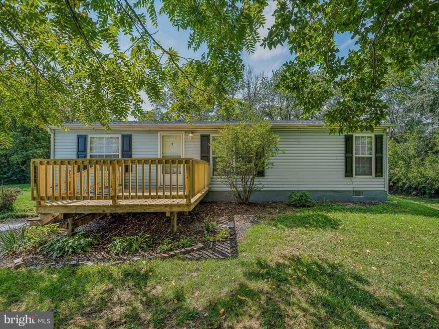 Manufactured home on a permanent foundation. Will qualify for VA and FHA financing at 0% down and 3.5% down respectively. Priced at recent appraisal. Single level living at its finest! This 3 bedroom 2 bath rancher sits on just under an acre and flooring has been updated throughout. When you pull up to the property you will notice the large gravel driveway for tons of off street parking. A concrete walkway leads you to the large porch, ready for rocking chairs. Inside you have a spacious living room with large windows, easy-care laminate floors, and a ceiling fan. A case opening leads you into the eat-in kitchen. You have ample countertop and cabinet space. There is room for a table by the large window for lots of natural light. Beyond the kitchen is your laundry room with hook-ups and shelving. As this room has a door to the rear yard it would be a perfect mudroom. Down the hall you have two generously sized bedrooms with bright windows, carpet, and ample closet space. The hall bath features an extended single bowl vanity for storage and a tub/shower combo. The primary suite features large windows for lots of a natural light and comfortable carpet. You have a large closet and a private ensuite with an extended single bowl vanity and tub/shower combo. Outside in the rear of the home you have a nice deck to host BBQs or lounge and take in the view. Stairs step down to the rest of your nearly 1/2 acre lot. The property backs to trees for lots of privacy. There's plenty of space to enjoy the outdoors. This home has everything you want at a price you can afford! Schedule your showing today!