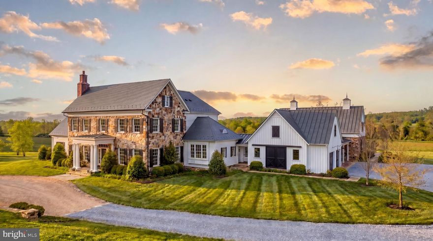 Set amid 53 acres of protected Virginia countryside in the heart of The Plains, Look Up Farm stands among the Capital Region’s most remarkable private estates. Surrounded by blue ridge mountain vistas on the front of the home, while the back of the home enjoys rolling pastures and horses grazing in the distance, pastoral countryside views and hay bales resting on the land in spring and fall. The property evokes the character of an upper-crust Colonial-era estate. Completed in 2020 through the collaboration of Potomac Valley Builders and Foster Zimmerman Architects, the home achieves a level of refinement rarely encountered among newly built country properties. 

A long, sweeping approach reveals a façade of vibrant old-world stone and clapboard beneath a slate and metal roof, accented by copper gutters and custom milled wood shutters. Windsor windows frame pastoral views in every direction, while balanced proportions and classical symmetry establish an immediate sense of quiet authority. The traditional center hall foyer introduces 11,850 finished square feet arranged with clarity and intention, anchored by a dramatic double-height stair hall crowned by a Ralph Lauren lantern with lift.

The great room centers on an Isokern Bvetto fireplace and opens seamlessly to the expansive rear terrace. Craftsmanship is evident throughout, from ten-inch-wide French oak flooring to one-and-a-quarter-inch TruStile paneled doors finished with Emtek hardware. Refined millwork creates a gallery-like backdrop for bespoke lighting by Visual Comfort, Urban Electric, and Hector Finch. Select spaces introduce depth and character, including a stately library finished in Farrow & Ball De Nimes Blue and a formal dining room positioned along a transverse gallery that separates entertaining and living spaces. 

At the heart of the residence lies the chef’s kitchen, designed for both daily living and large-scale entertaining. Custom inset cabinetry and Vermont Danby marble frame a substantial center island, while a Wolf dual-fuel range anchors a comprehensive appliance suite with integrated Sub-Zero refrigeration and a built-in espresso system. A fully appointed butler’s pantry enhances functionality.

The main-level primary suite occupies a private wing with direct terrace access, a masonry fireplace, generous dressing space, and a spa-inspired marble bath with a glass-enclosed shower and built-in soaking tub. A separate guest wing offers exceptional flexibility with two ensuite bedrooms, full kitchen, office, and independent living spaces.

Upstairs, four additional bedroom suites each feature en suite baths and walk-in closets, alongside a sitting room, wet bar, and secondary laundry. In total, the residence includes eight bedrooms, nine full baths, and three half baths.

The lower level is designed for leisure and gathering, anchored by a recreation room with a full wet bar and complemented by a dedicated home theater with enhanced sound insulation and integrated audiovisual systems. An exercise room, additional bath, and bunk rooms complete the level with direct terrace access.

Behind the scenes, an elevator, whole-house generator, Carrier HVAC, security system, Sonos audio, and Savant automation are seamlessly integrated. Exterior lighting casts a warm glow at dusk, reinforcing the home’s timeless architectural character.

The surrounding acreage unfolds into sweeping lawns, mature tree lines, and expansive vistas characteristic of this storied equestrian region, offering privacy while remaining within convenient reach of Middleburg and Washington. 

With its scale, architectural integrity, curated finishes, and advanced systems, Look Up Farm stands as a rare offering. It is a newly built country estate that honors classical design while delivering the expectations of modern living, crafted not simply as a residence but as a generational property of lasting significance within one of Virginia’s most enduring landscapes.