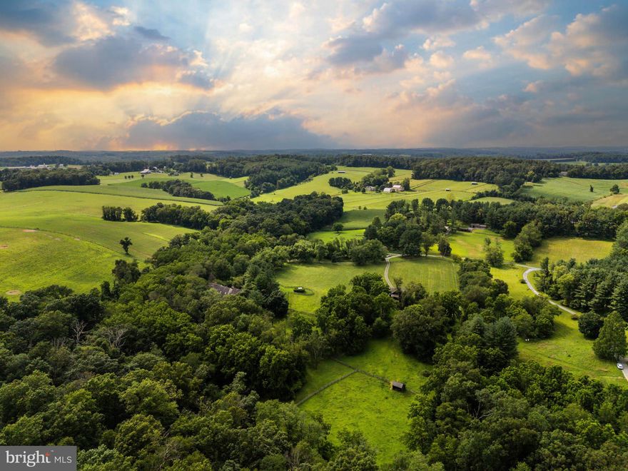 Live authentically. Stones Throw Farm. Set in the heart of Greenspring Hunt Country, this exceptional 18.01 acre estate offers unrivaled privacy amid gently rolling pastures. A meandering tree-lined drive heightens your sense of arrival, as sweeping panoramic views unfold all around. The landscape is embraced by a meandering stream on three sides with walking trails... quite remarkable. The plantings are masterfully composed, framing epic sunrises and sunsets. The home’s architecture balances rustic authenticity with refined comfort. A first-floor primary suite with spa bath features premium views of your beloved animals in the pasture beyond. The expansive cooking space invites convivial gatherings, opening seamlessly to a generous deck and patio designed for effortless entertaining. A state-of-the-art equestrian barn over-engineered where supreme functionality meets beauty. Bespoke chicken coop redefines pastoral indulgence. Here, the rhythms of nature shape daily life—birdsong at dawn, open skies at dusk, and the abiding calm of land and water in perfect harmony. Stargazers rejoice... your very own celestial observatory. Take photos and ponder the cosmos. Xfinity Internet. Cultivate your existence. The art of uniting human and home.