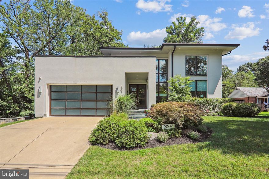 Experience luxurious living in this modern masterpiece located in the highly sought-after Crestwood neighborhood of Washington, DC. This exceptional contemporary residence showcases a sophisticated blend of glass, lighting, soaring ceilings, and wood elements, offering an unparalleled living experience just steps from Rock Creek Park. Revel in the prime location and the stunning interior of this home, featuring sunlit rooms, expansive windows, high ceilings, Maple wood flooring, and inviting open living spaces complemented by excellent outdoor areas.

This distinctive home offers an inviting front entry with elongated glass and wood doors leading to a dramatic great room with a gas fireplace and a unique accent wall with display shelving, an elegant dining room, and an outstanding open professional style show kitchen. The top-of-the-line chef’s kitchen is equipped with exquisite Cherry cabinets with soft-close drawers, solid surface countertops (Urbatek by Porcelanosa), a GE Monogram appliance suite, a wine refrigerator, and two islands. The sun-drenched breakfast room, with a wall of windows, opens to a tiered stone terrace with bucolic views. The spirit of this home lies in its open-concept floor plan, with its integrated cooking, entertainment, and relaxation zones.

The luxurious main level primary bedroom suite includes custom blackout blinds, an expansive walk-in closet with an organizing system, and a sumptuous spa bathroom with a double vanity, a deep soaking tub, and a separate glass-enclosed shower. The primary suite also has access to the rear terrace and offers gorgeous, treed views. The main level is complete with a sleek powder room and a light-filled bedroom / office with custom desks.

The upper level offers two additional oversized en-suite bedrooms with attached bathrooms, a bonus room/yoga room, and a versatile landing area.

Downstairs, there is a huge walk-out recreation room with recessed lighting and a speaker system, a fitness room, a spacious private en-suite fifth bedroom / AuPair suite, a dual entry bathroom, fabulous laundry room with a voluminous storage room, and an outside entrance with a stone patio. The lush, fenced backyard features mature landscaping, a built-in gas line to the grill, and a multi-level stone terrace – perfect for entertaining!

Crestwood is valued for its convenient location, elegant homes on quiet tree-lined streets, and proximity to Rock Creek Park. Rock Creek Park provides miles of paved bicycle paths, as well as foot and horse trails that wind along the creek and through the woodland. The park also boasts an outdoor concert and theater venue, a tennis stadium, a planetarium, and a nature center. This wonderful home is just 0.8 miles from the Red Line metro station and minutes from the dining and entertainment centers of downtown DC.