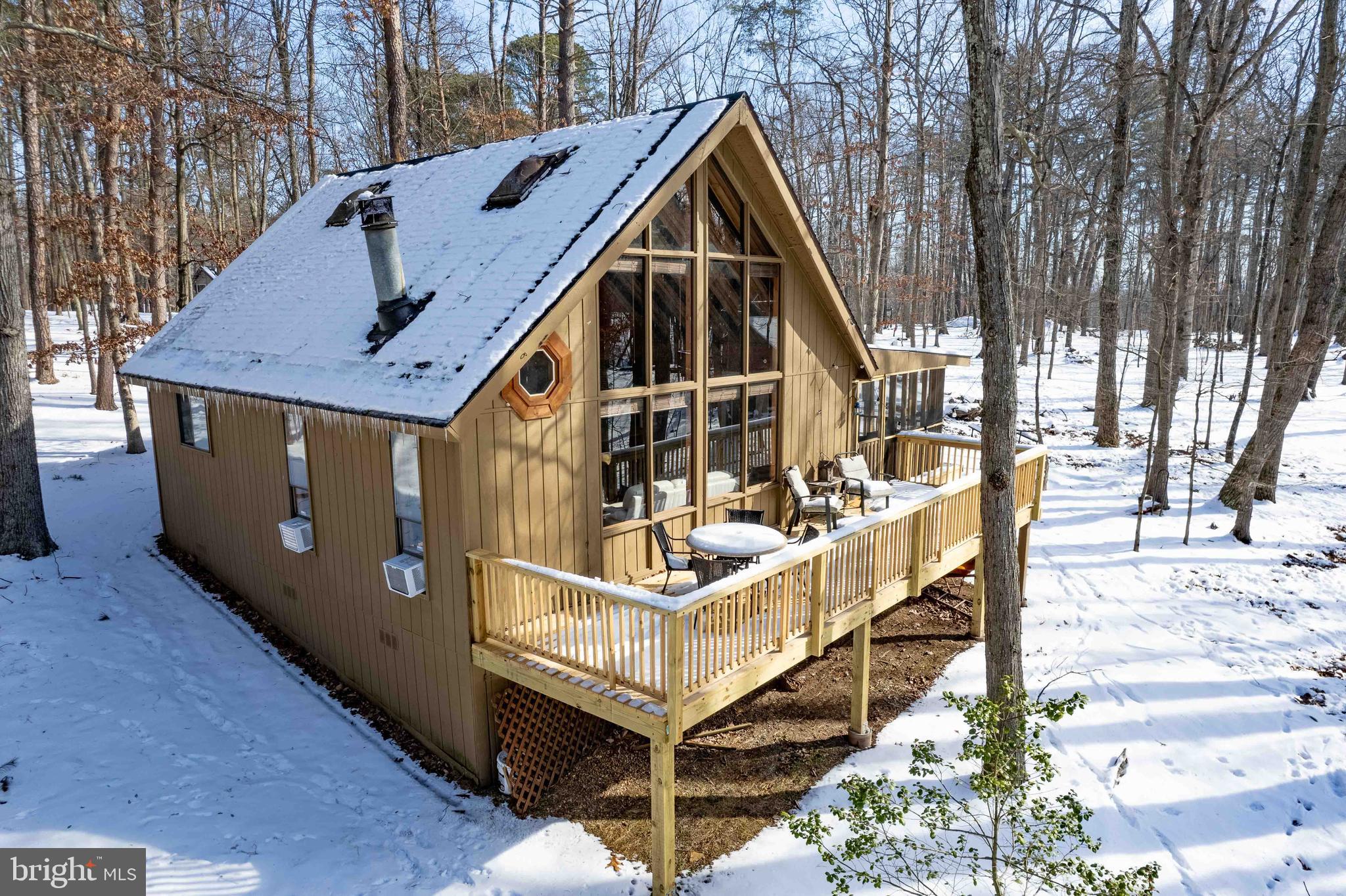 Nestled in a serene cul-de-sac, this charming chalet-style home boasts captivating wooded views, providing a tranquil retreat in The Woods community. Unwind on your screened porch or expansive open deck, savoring your morning coffee amidst the symphony of nature and local wildlife. The cozy cabin offers a main-floor bedroom and a loft bedroom with an en suite.
Step into the inviting great room featuring knotty pine cathedral ceilings adorned with wood beams, wood-paneled walls, and six-panel wood doors. The ambiance is enhanced by a Timberline wood stove, offering warmth and charm, while a wall of windows frames the picturesque wooded landscape. A covered entry beckons you inside.
Recent upgrades, including a new Goodman HVAC system, a new Goodman Outside Air System, a new Goodman Heat Pump, a new Goodman line set, and a brand-new outside deck and sunroom, add modern comfort and efficiency to an already inviting space.
The property comes furnished, with most of the furnishings conveying with the sale, making it Air Bnb ready. This turnkey feature enhances the property's appeal for those looking for a hassle-free transition into the vacation rental market.
The main level includes a full bath and a convenient laundry room. This property beckons those seeking a perfect blend of comfort and natural beauty. Schedule your appointment to explore this exceptional residence.
Additionally, a Class A FAMILY membership is available. Noteworthy private club amenities, such as golf (greens fees), a driving range, indoor sports center, outdoor pools, clubhouse, and more, await. It's important to note that these amenities are not owned or operated by the HOA, and their dues are separate. Take advantage of the array of offerings, from sports facilities to dining at The Clubhouse Grille & Pub or indulging in relaxation at the Sleepy Creek Spa & Salon—all within this idyllic community.
