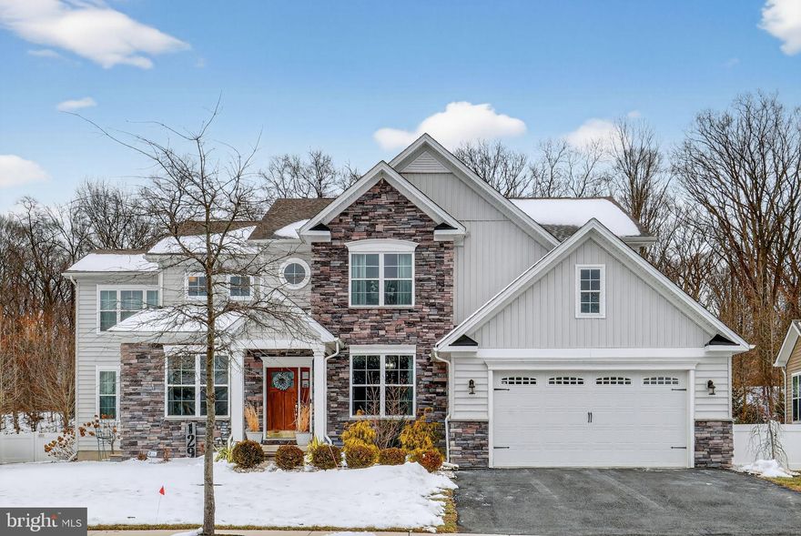 Masterful design meets modern luxury in this stunning 6-year-old contemporary stone Colonial offering an impressive 6,215 square feet of finished living space. This expansive 5–6 bedroom, 3½-bath home delivers exceptional scale, thoughtful upgrades, and elegant architectural details throughout. From the moment you arrive, curb appeal shines with manicured landscaping, new hardscaping, decorative columns and barn-style two-car garage doors. Inside, natural light pours through walls of windows, illuminating 9-foot ceilings, designer lighting, and rich hardwood and LVP floors that flow seamlessly across every level of this gorgeous home (No carpet!). The formal living and dining rooms showcase classic crown molding, while the breathtaking gourmet kitchen serves as the heart of the home, perfect for entertaining on any scale. Highlights include a 36-inch gas cooktop with pot filler, professional range hood, electric double wall oven, in-drawer microwave, farmhouse sink, side-by-side touchscreen SMART refrigerator, quartz countertops, upgraded white cabinetry with glass uppers, full-wall designer backsplash, butler’s pantry, oversized center island with seating, breakfast bar, and a separate dining area. An adjoining morning room opens to the deck through sliding glass doors, ideal for morning coffee or sunset views, while the centrally located great room invites gathering and relaxation. A stylish powder room, an oversized pantry off the garage that was converted to a second laundry room, complete the main level. Upstairs, retreat to the spacious owner’s suite, featuring two walk-in closets, including a boutique-style dressing room with custom organizers valued at over $10,000 and charming farmhouse doors. The spa-inspired owner’s bath includes a water closet, Jacuzzi whirlpool tub (with a second hot water heater), and a European-style shower. Three additional generously sized bedrooms, a full hall bath, linen closet, and convenient second-floor laundry (two laundry rooms in the house) complete this level. The fully finished basement significantly expands the living space, offering two additional bedrooms (one ideal for a home office), a full bath, exercise room, bar area, and abundant storage, bringing the home’s total finished space to an exceptional 6,215 square feet. The private fenced-in yard backs to wooded open space, enhancing the home’s tranquil setting. Located in the prestigious Meridian Crossing community, residents enjoy low-maintenance living with an association fee that covers lawn care, snow removal, trash service, and access to a luxury clubhouse with pool, fitness center, picnic areas, and movie room. Conveniently located minutes from Route 1 and I-95. This remarkable home offers space, style, and sophistication rarely found—schedule your private tour today.