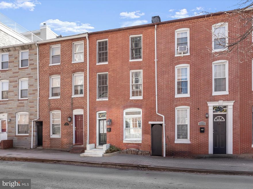 Nestled in the heart of Federal Hill, this beautifully updated three bedroom, two bathroom home offers timeless charm with modern updates. Multiple outdoor spaces, including a two-level rooftop with sweeping city views, offer incredible opportunities for relaxation and entertaining. A deeded parking spot in a secure garage adds unbeatable convenience. As you arrive, a stained glass transom window above the front door sets the tone for the character found throughout. Original hardwood floors, exposed brick walls, a neutral color palette, and sun-filled windows create a warm, inviting atmosphere. The main level features a cozy front living room and a spacious dining area, separated by stately columns. Renovated in 2020, the eat-in kitchen impresses with stainless steel appliances, gas cooking, a pantry, an accent tin ceiling, glass display cabinets with underlighting, a butcher block island, and heated floors. A glass door leads to a charming brick patio—perfect for al fresco dining. Upstairs, two generously sized bedrooms provide ample space, with one offering access to a private rear deck. The hallway bathroom includes a jetted tub-shower and a dual-sink vanity, while a laundry closet adds convenience. The top level is dedicated to the primary suite—an ideal retreat featuring a luxurious bathroom with a frameless walk-in shower that has dual shower heads and a bench. Down the hall, a built-in wet bar offers easy access to the two-level rooftop deck, making entertaining effortless. With fantastic views of the city skyline and M&T Bank Stadium, plus outdoor speakers, this space is destined to be a favorite gathering spot. Storage is abundant, with large closets throughout each level, and additional space in the unfinished cellar basement that is accessible from outside. Recent improvements include a new two-stage HVAC system, water heater with a twelve-year warranty, sump pump/dehumidifier, and an upgraded silicone roof. Located in one of Baltimore’s most sought-after neighborhoods, this home has easy access to everything Federal Hill has to offer. Enjoy the local favorites with top-rated restaurants, lively bars, boutique shops, and everyday essentials just around the corner. Scenic Federal Hill Park, with its breathtaking harbor views, is only a few blocks away, while Riverside Park and the Inner Harbor provide even more outdoor recreation. Quick access to downtown, major highways, and public transit ensures effortless commuting. A perfect blend of historic charm, modern updates, and incredible city living awaits!